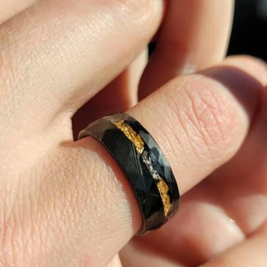 Close-up of a hand wearing a black ring with gold accents.