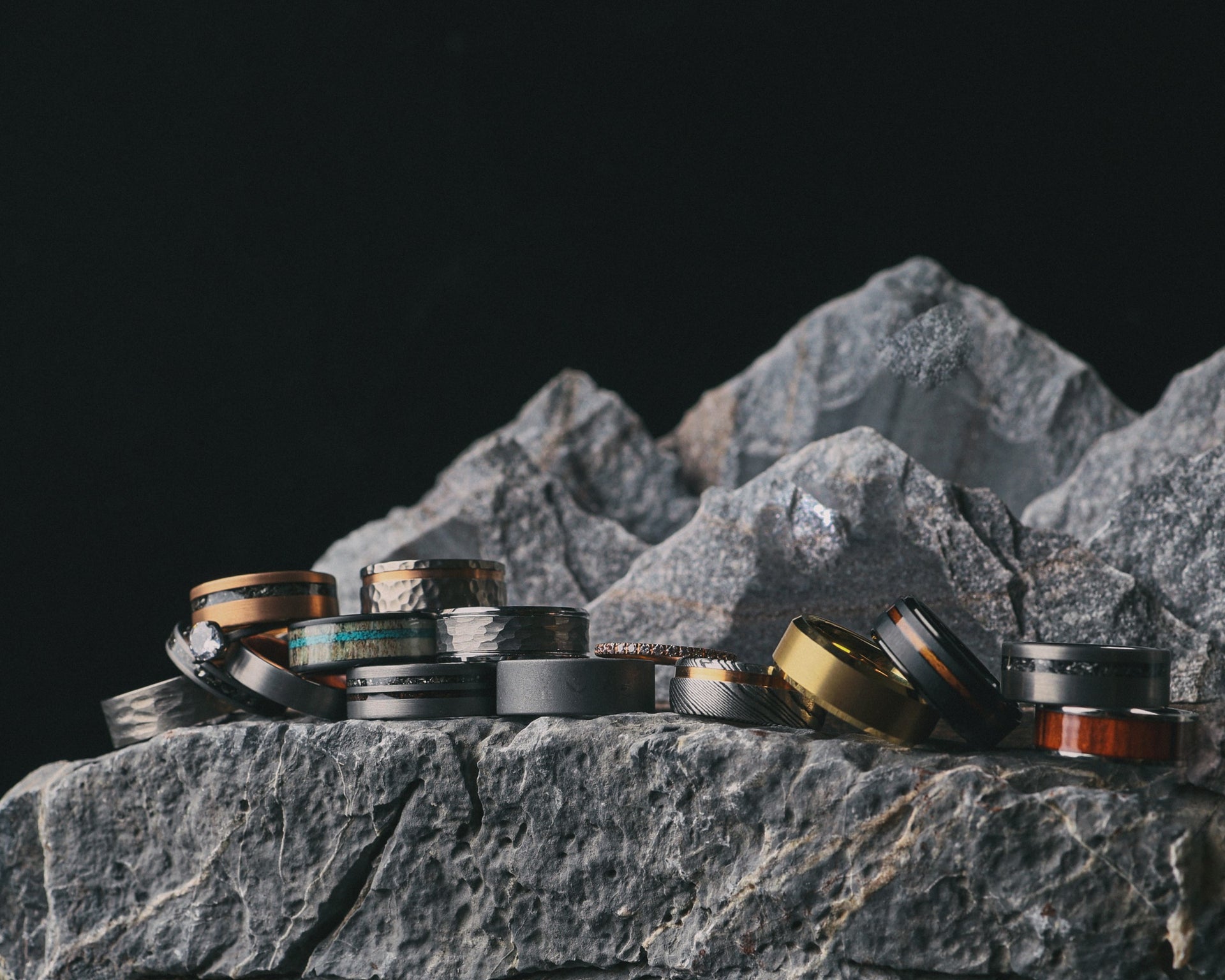 Various rings displayed on textured rocks against a dark background.