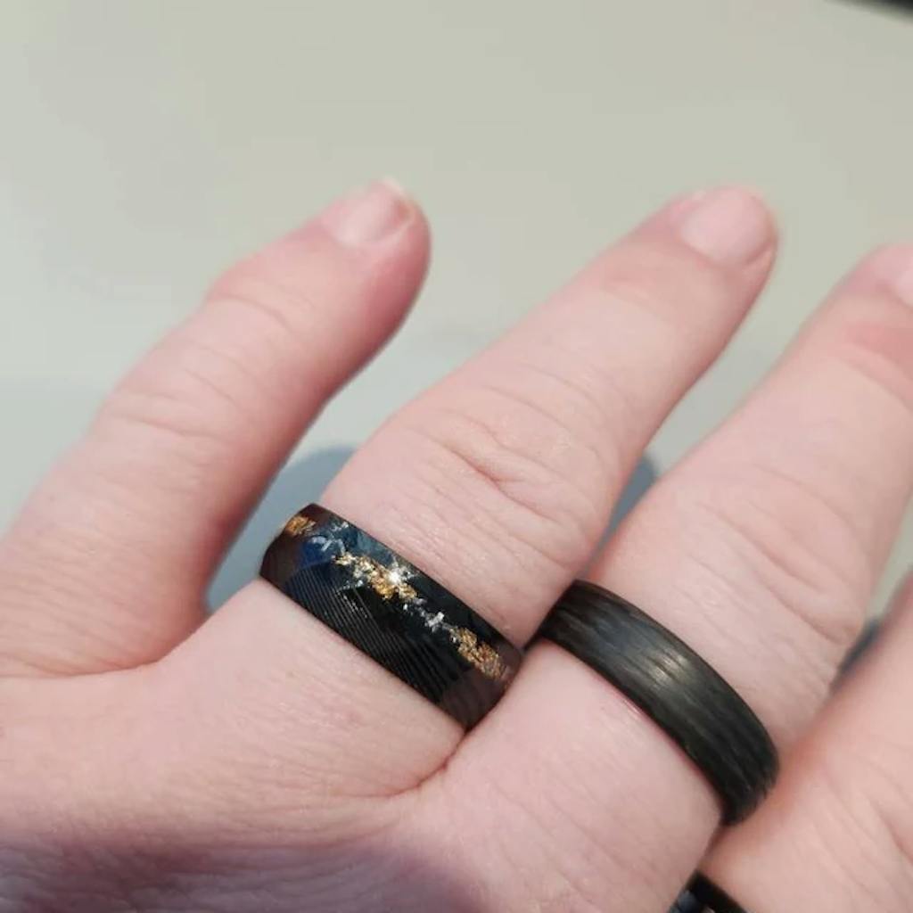 Close-up of a hand wearing two dark rings on fingers.