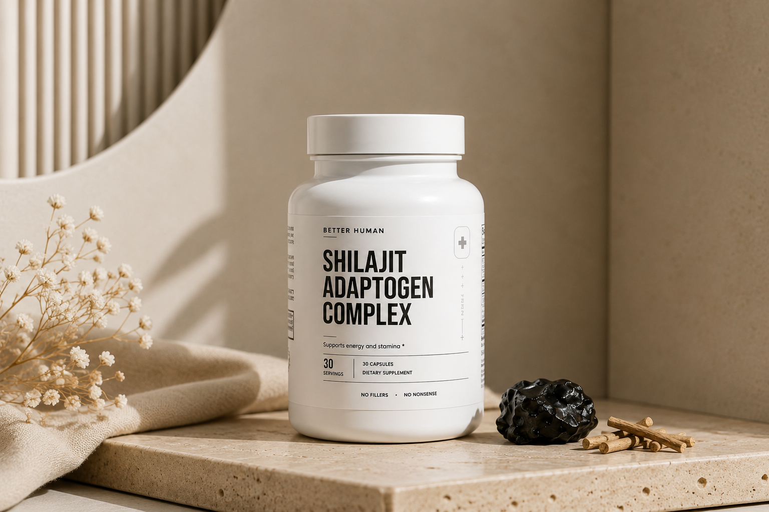 A white bottle of Shilajit Adaptogen Complex sits on a stone surface with flowers and raw ingredients.