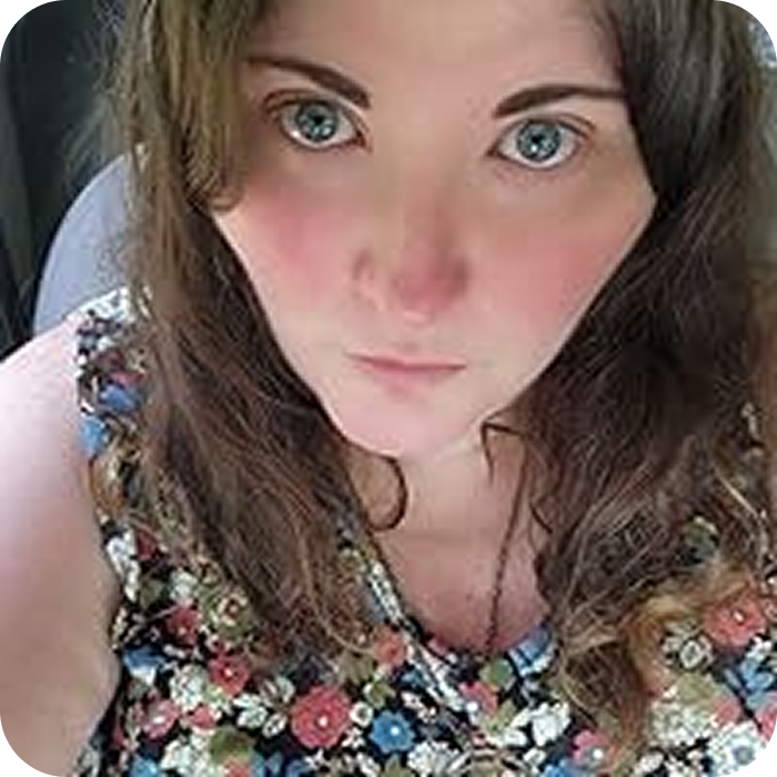 Person with long hair and floral top, looking at the camera.