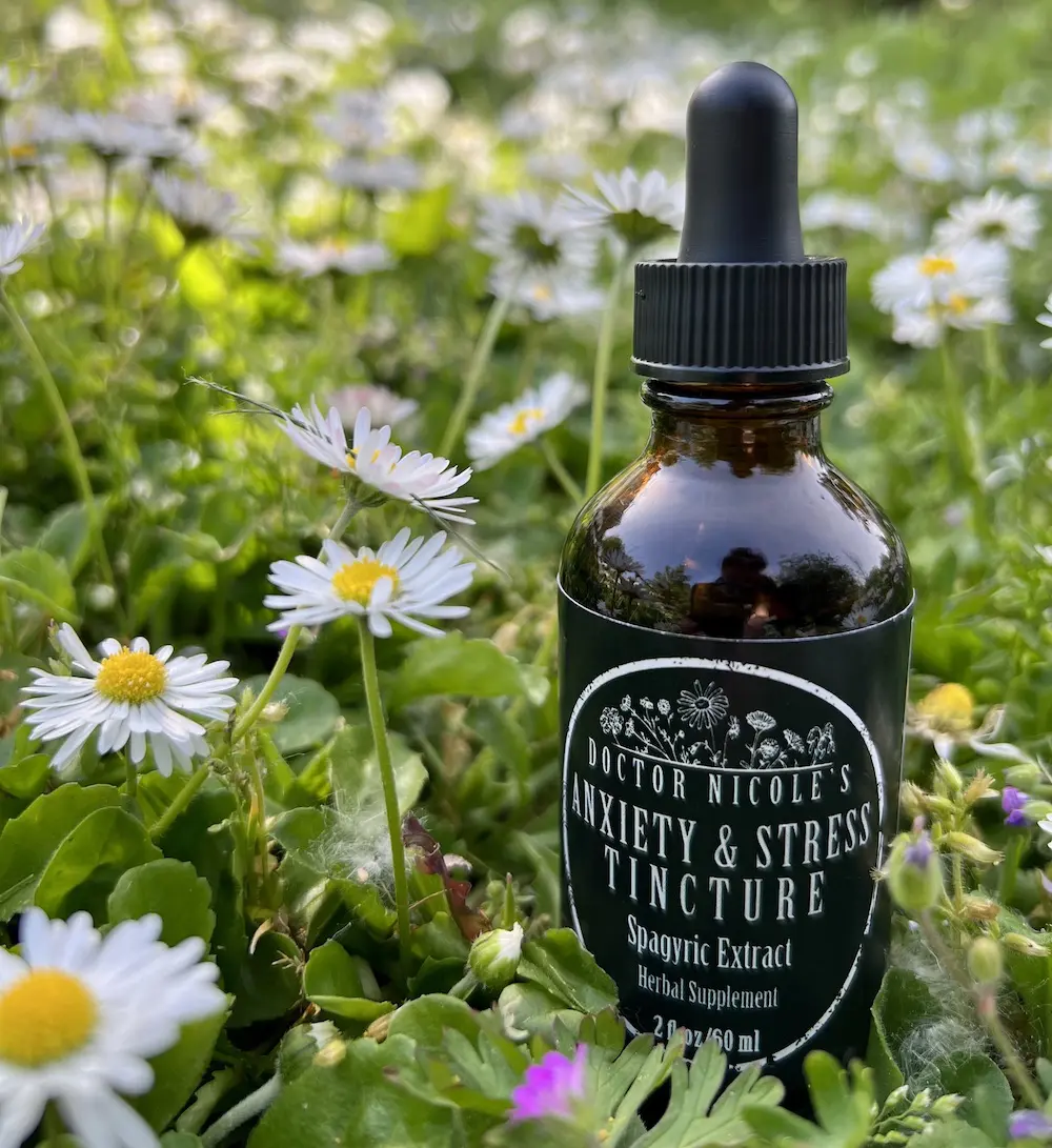 Brown tincture bottle labeled for anxiety and stress, surrounded by daisies.