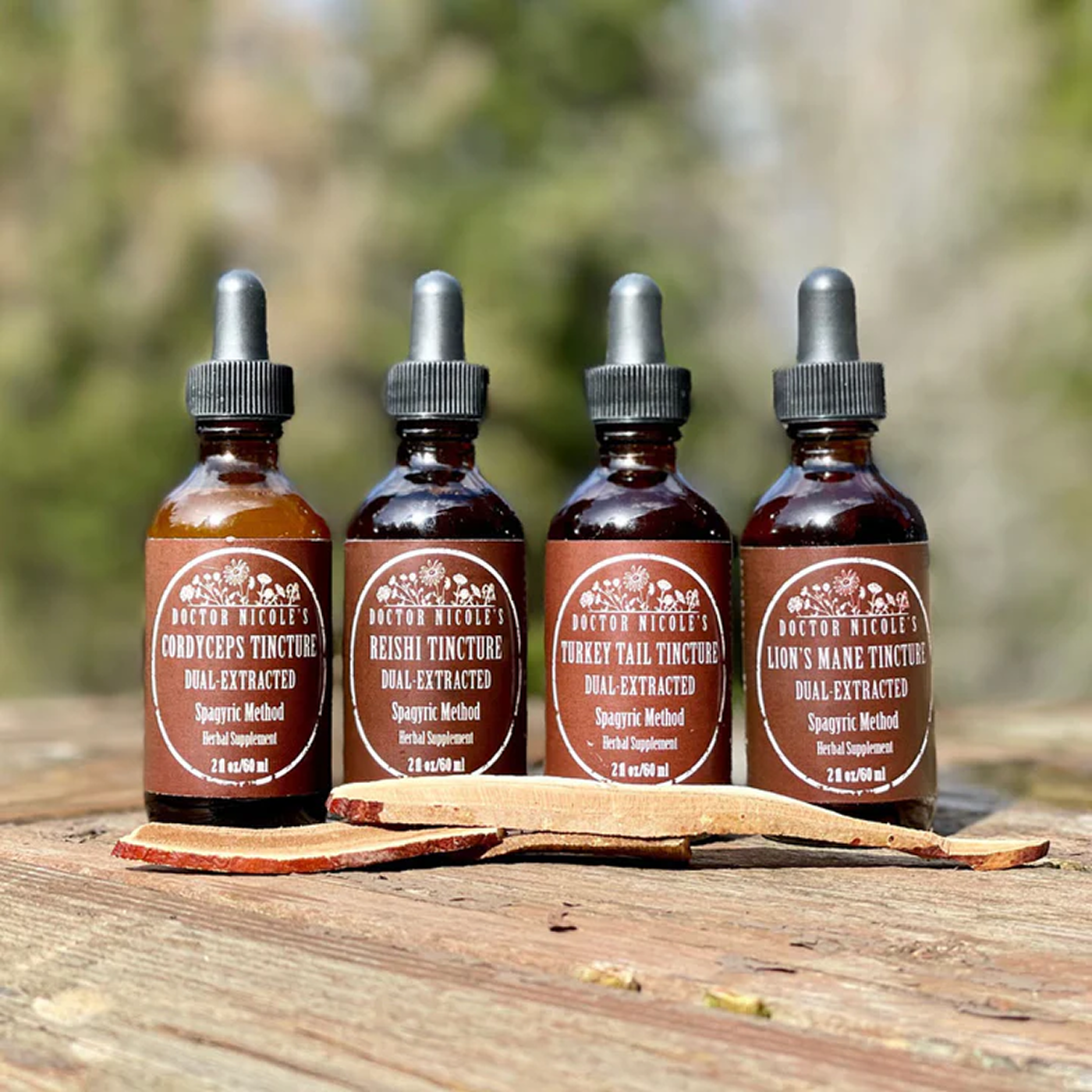 Four tincture bottles labeled with different mushroom extracts on a wooden surface.