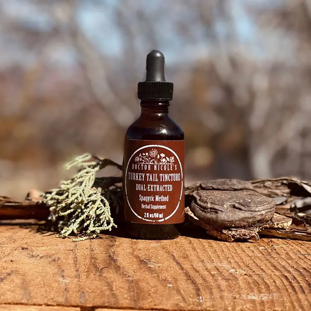 Brown bottle of turkey tail tincture with dried mushrooms on a wooden surface.
