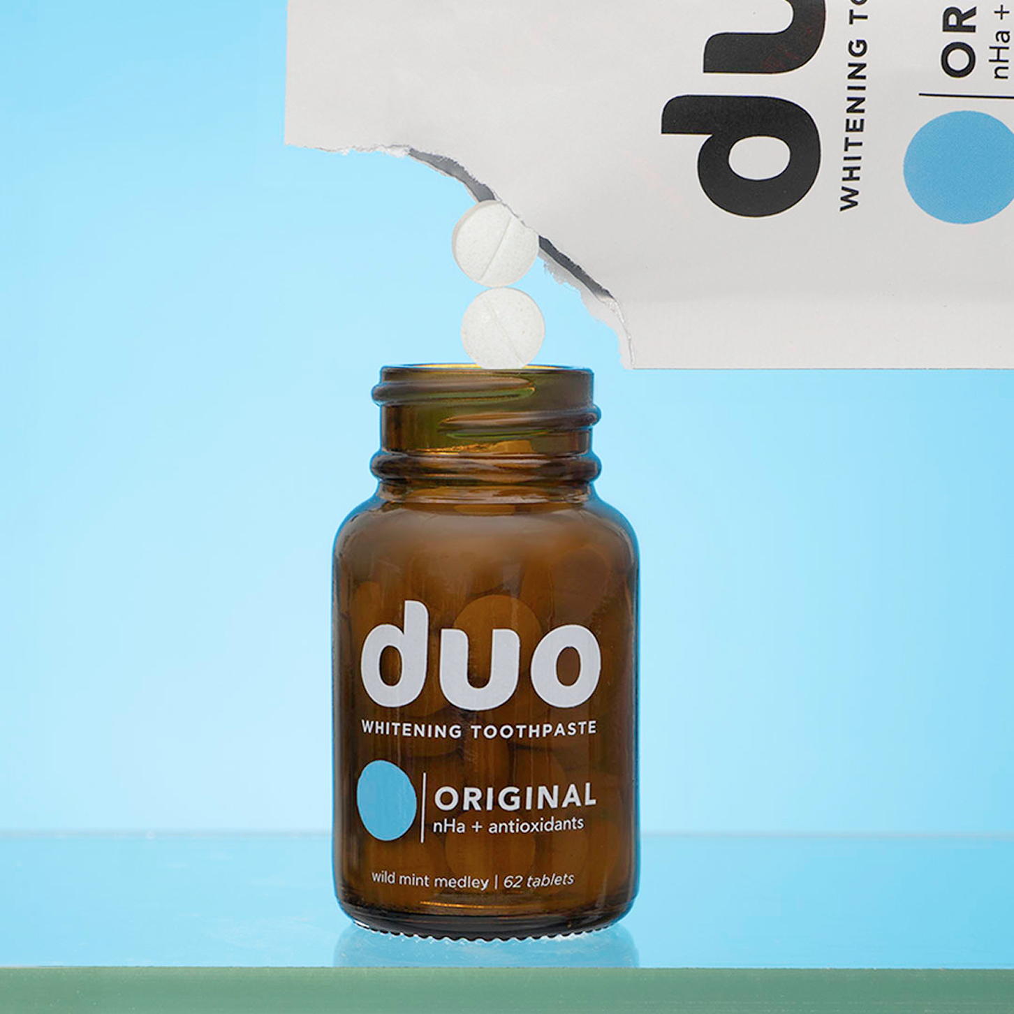Brown bottle labeled 'duo' with tablets falling from a torn package.