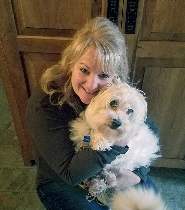 Person hugging a fluffy white dog indoors.