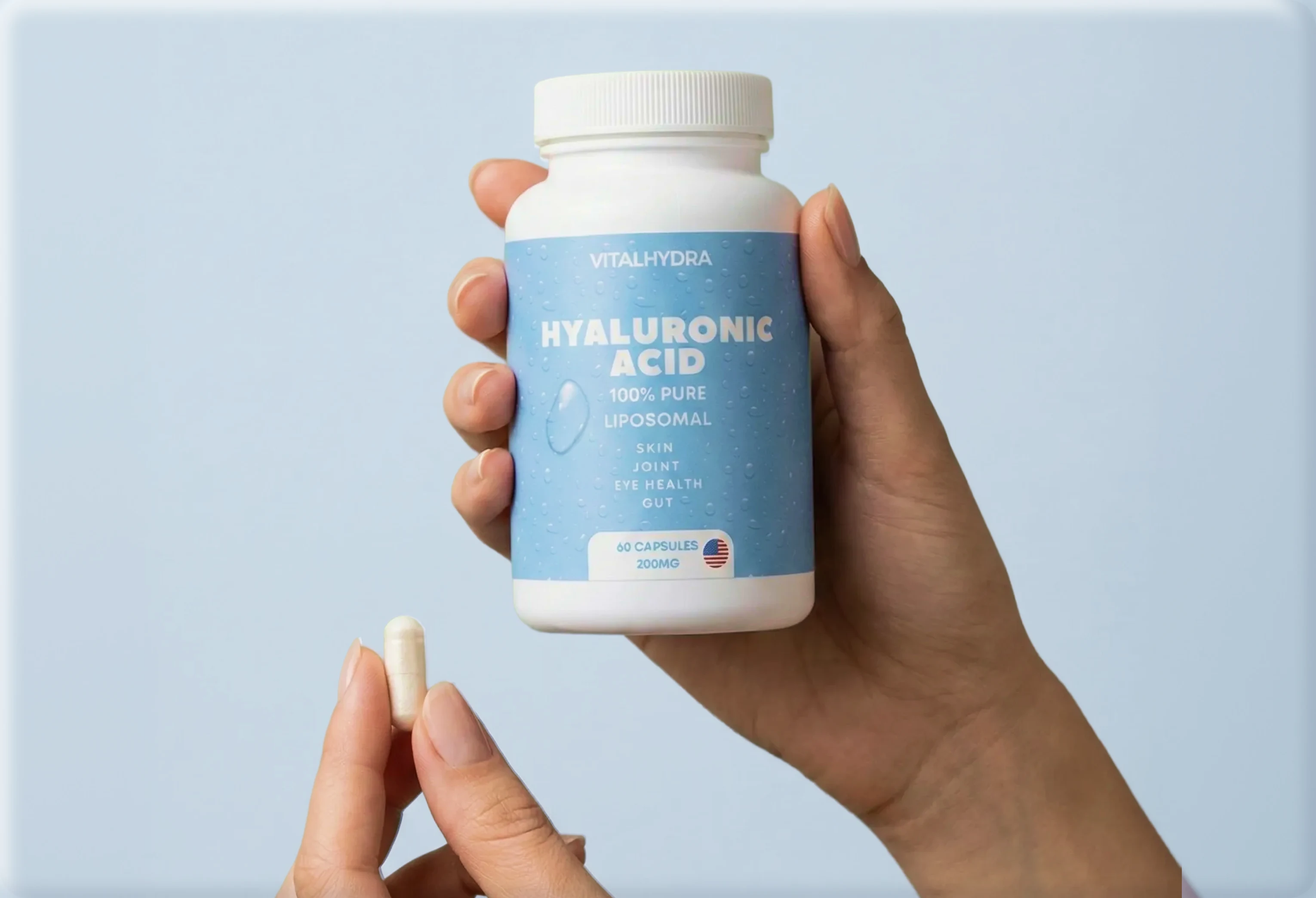 A person holds a bottle of Vitalhydra Hyaluronic Acid supplements in one hand and a single capsule in the other.