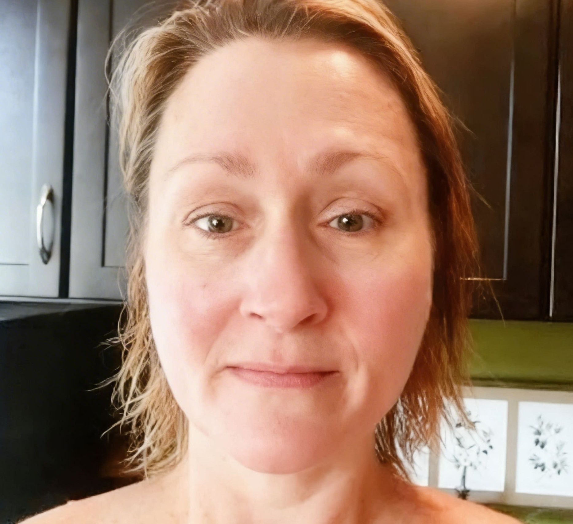 A close-up photo of a woman with light brown hair and green eyes looking at the camera.