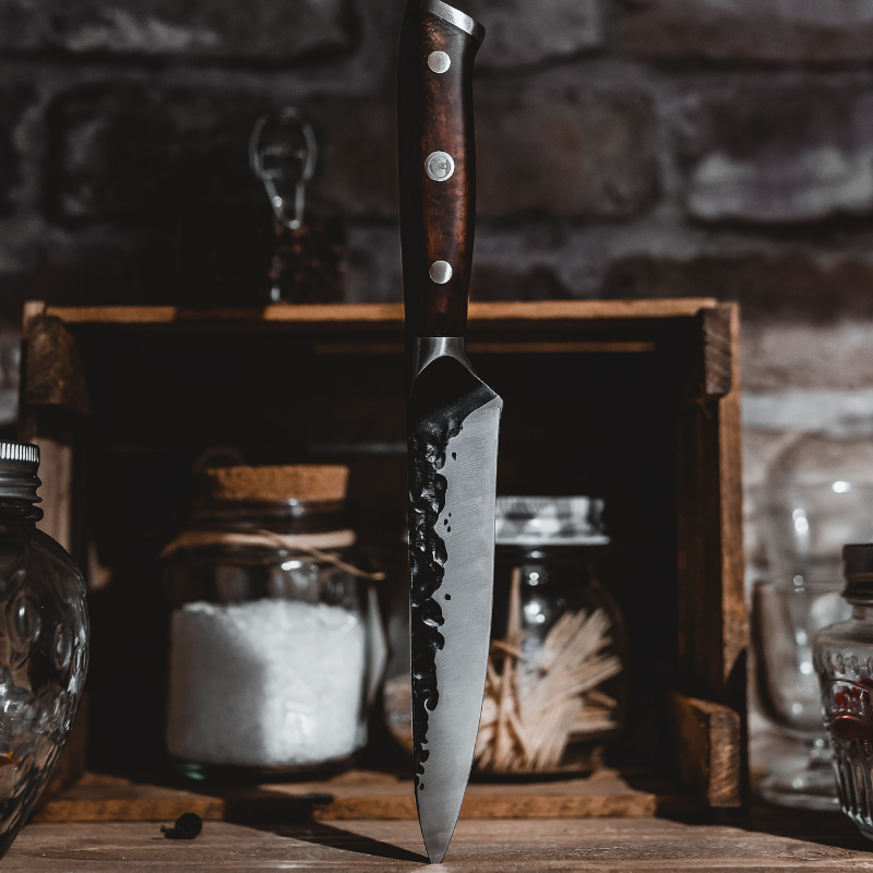 A knife with a wooden handle stands upright on a kitchen counter.