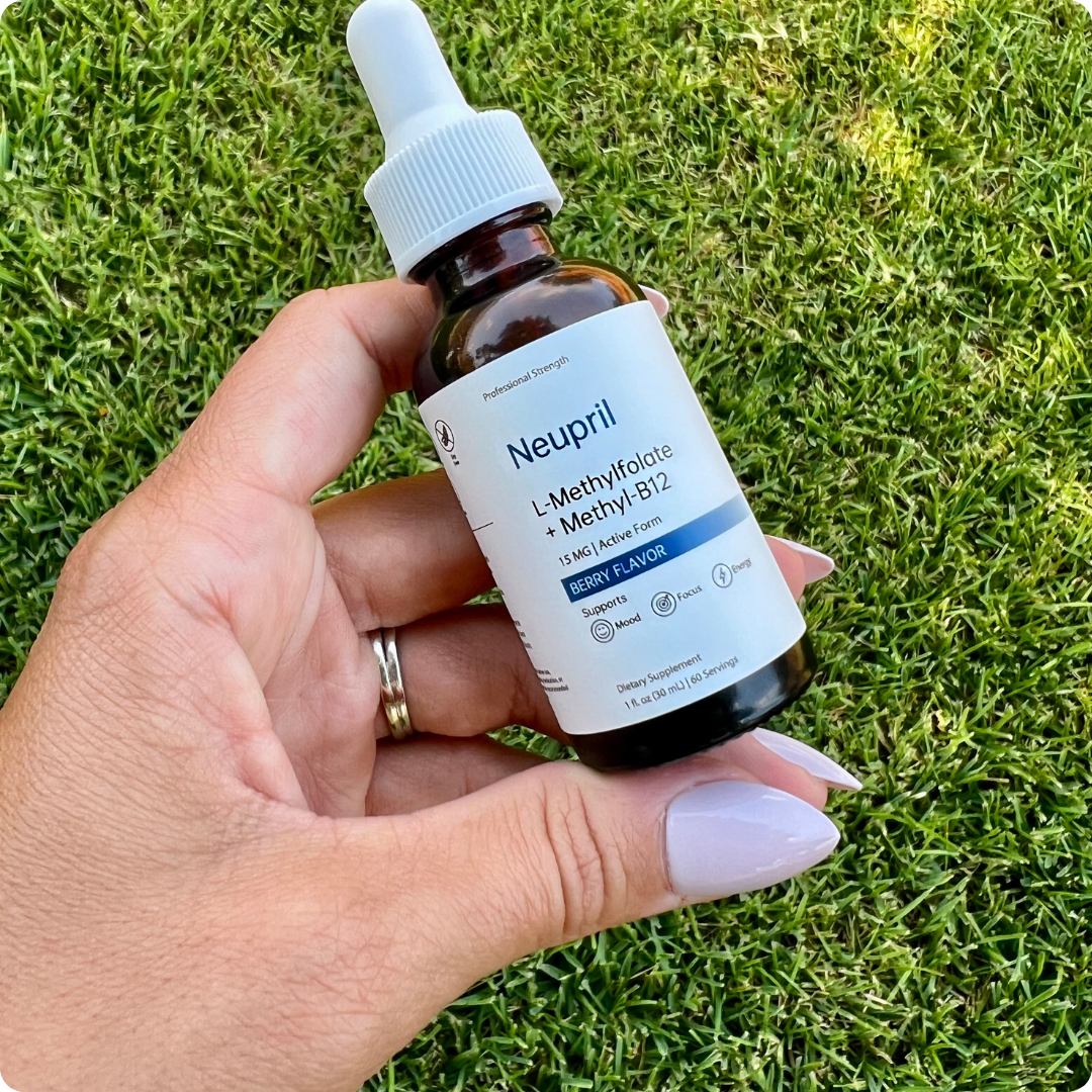 Hand holding Neupril L-Methylfolate + Methyl-B12 berry flavor liquid supplement bottle on grass background