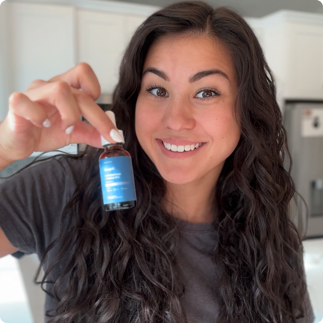 A smiling mother holding a bottle of Neupril Kids Formula L-Methylfolate + B12 in her kitchen
