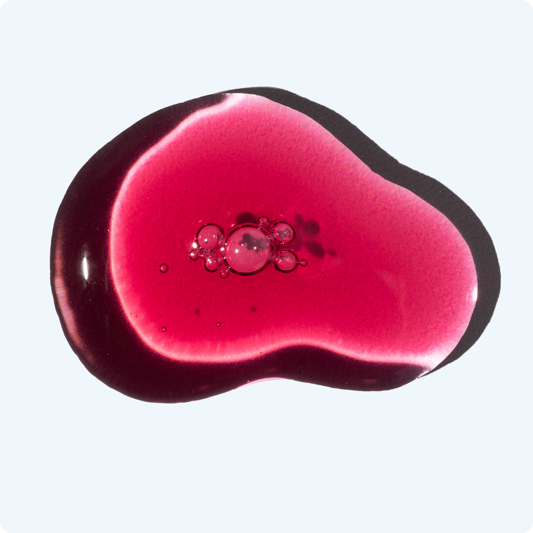 A pink liquid splatter with bubbles on a light background.