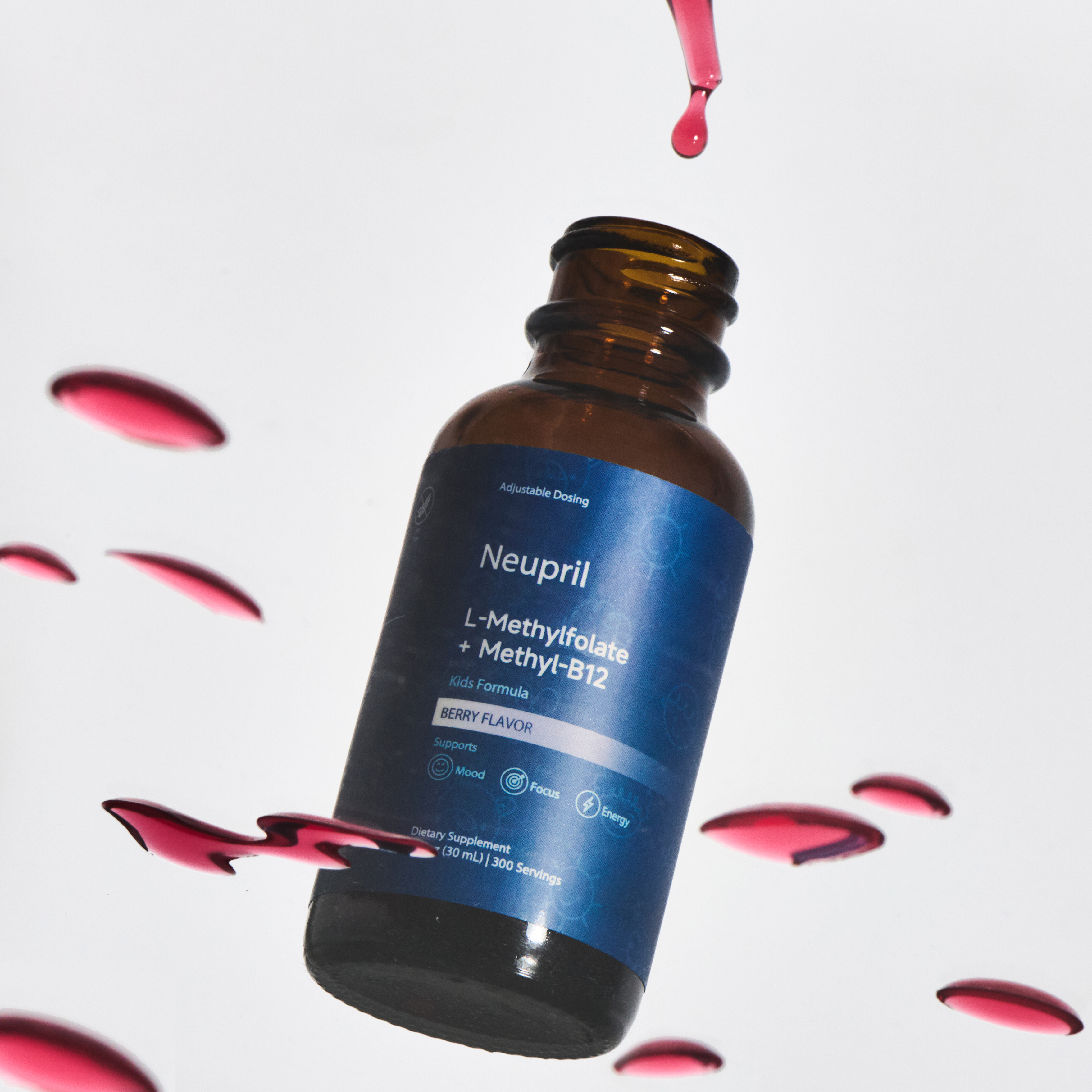 An open bottle of Neupril Kids L-Methylfolate + Methyl-B12 supplement with berry-colored liquid droplets around it, highlighting the kids’ formula and vibrant flavor