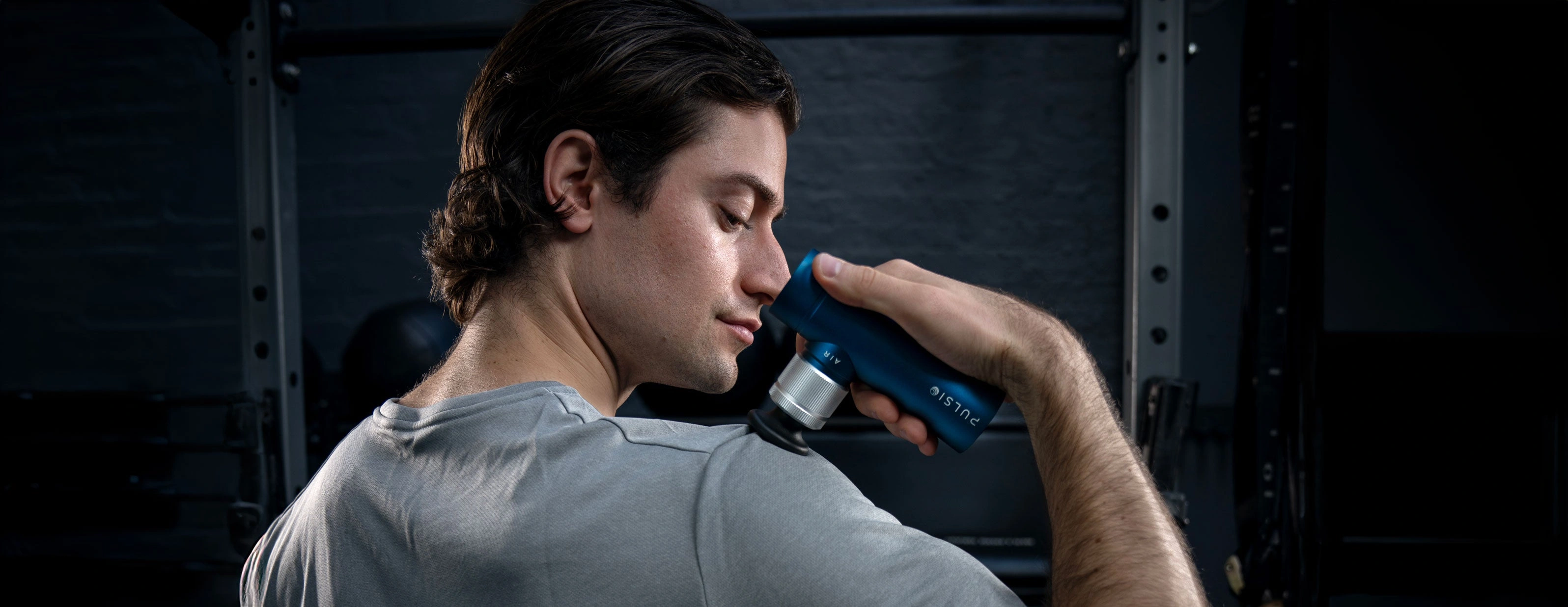 Person using a blue massage gun on their shoulder.