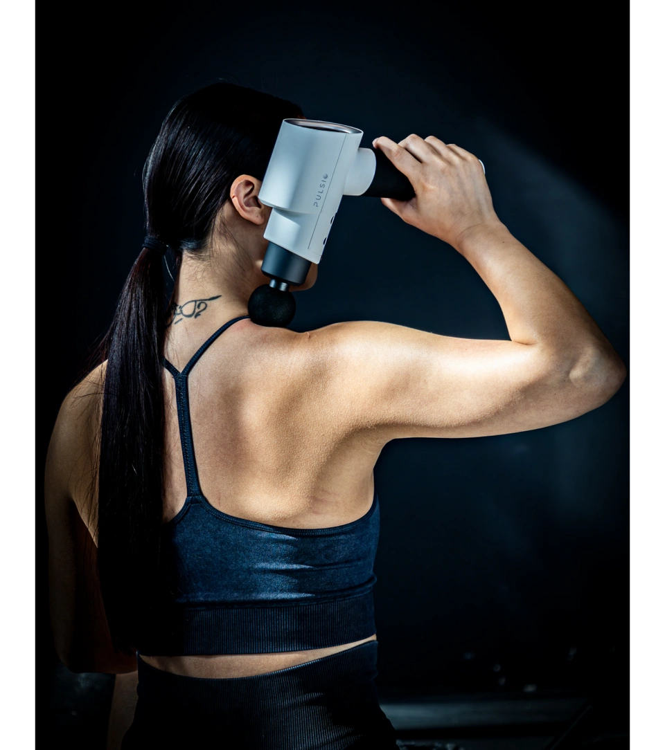 Person in workout attire using a massage gun on neck.