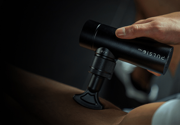 A hand holding a black massage gun on a person's arm.