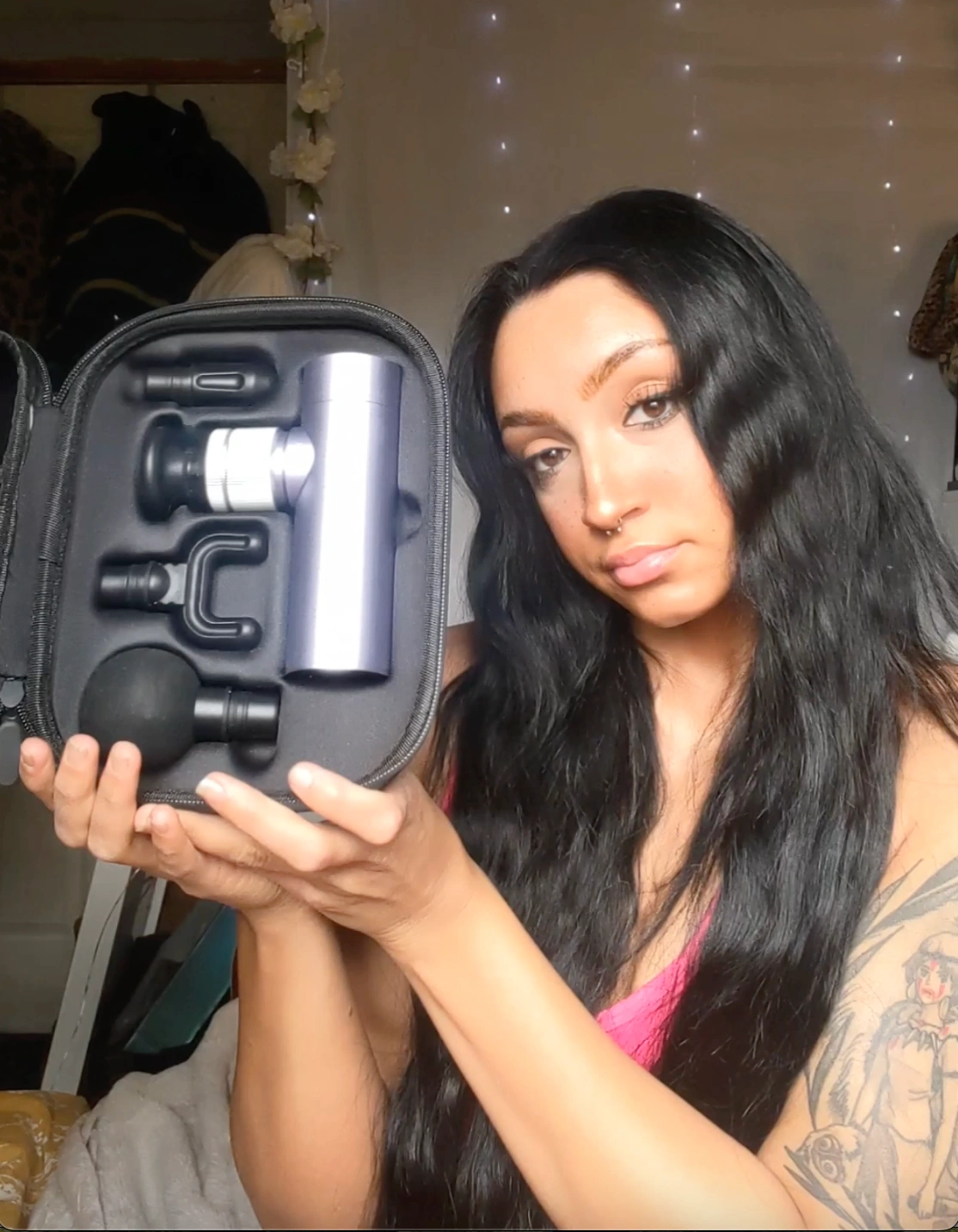Person showing a massage gun kit with multiple attachments.