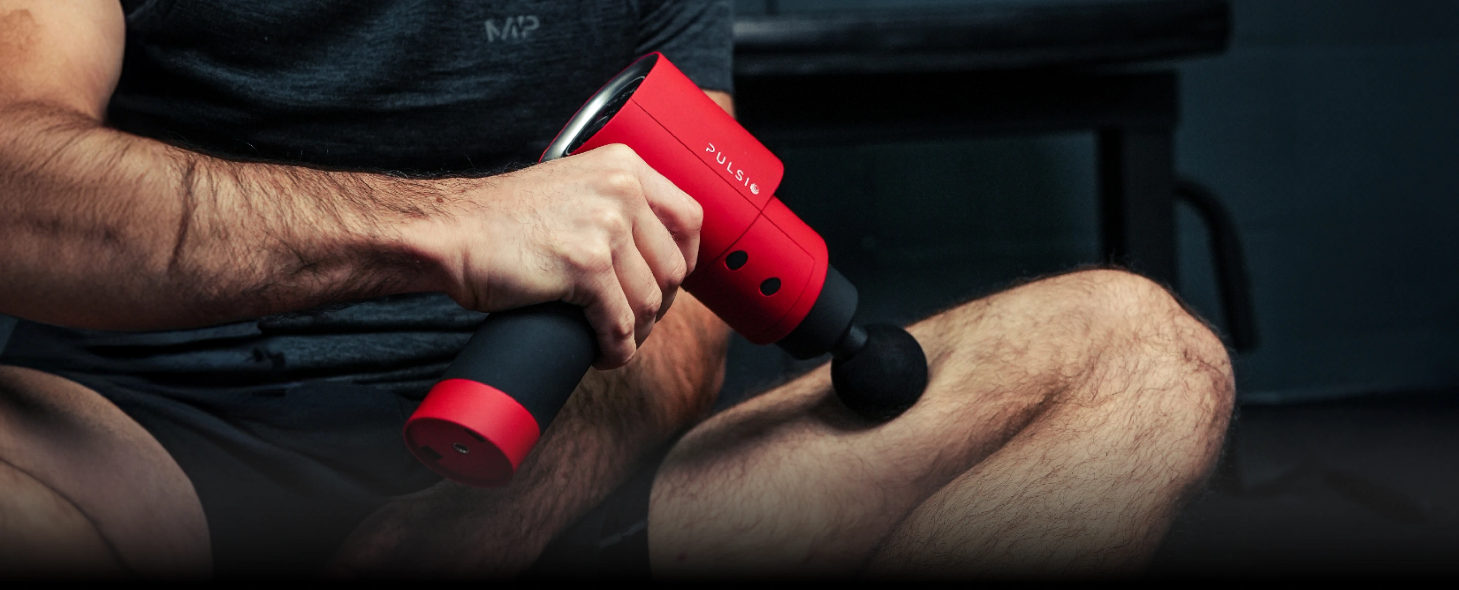 Person using a red massage gun on leg.