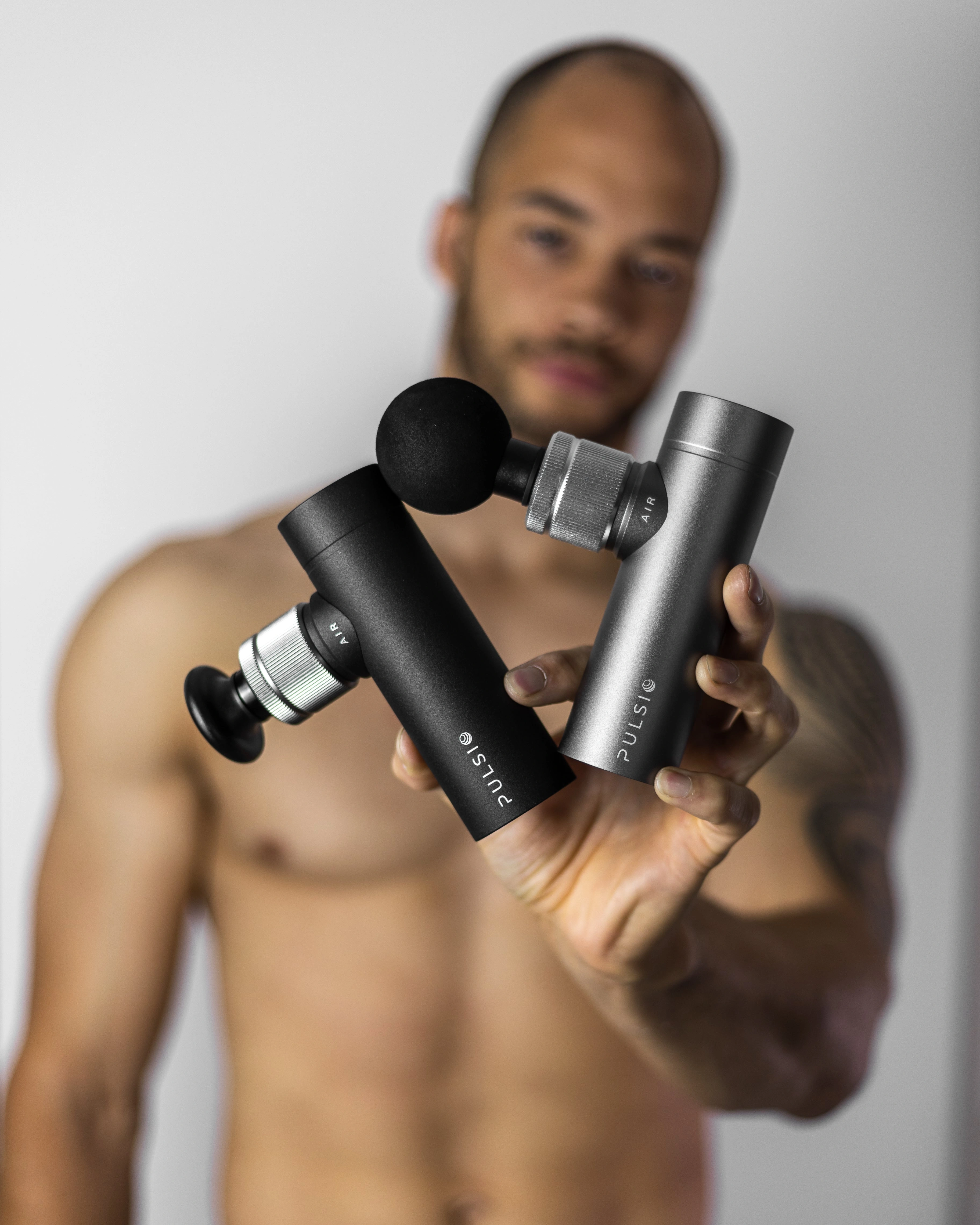 A person holding two handheld massage devices with rounded attachments.