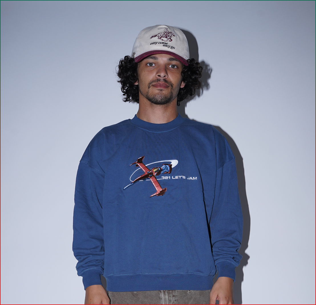 Person wearing a blue sweater with a graphic design and a white cap.