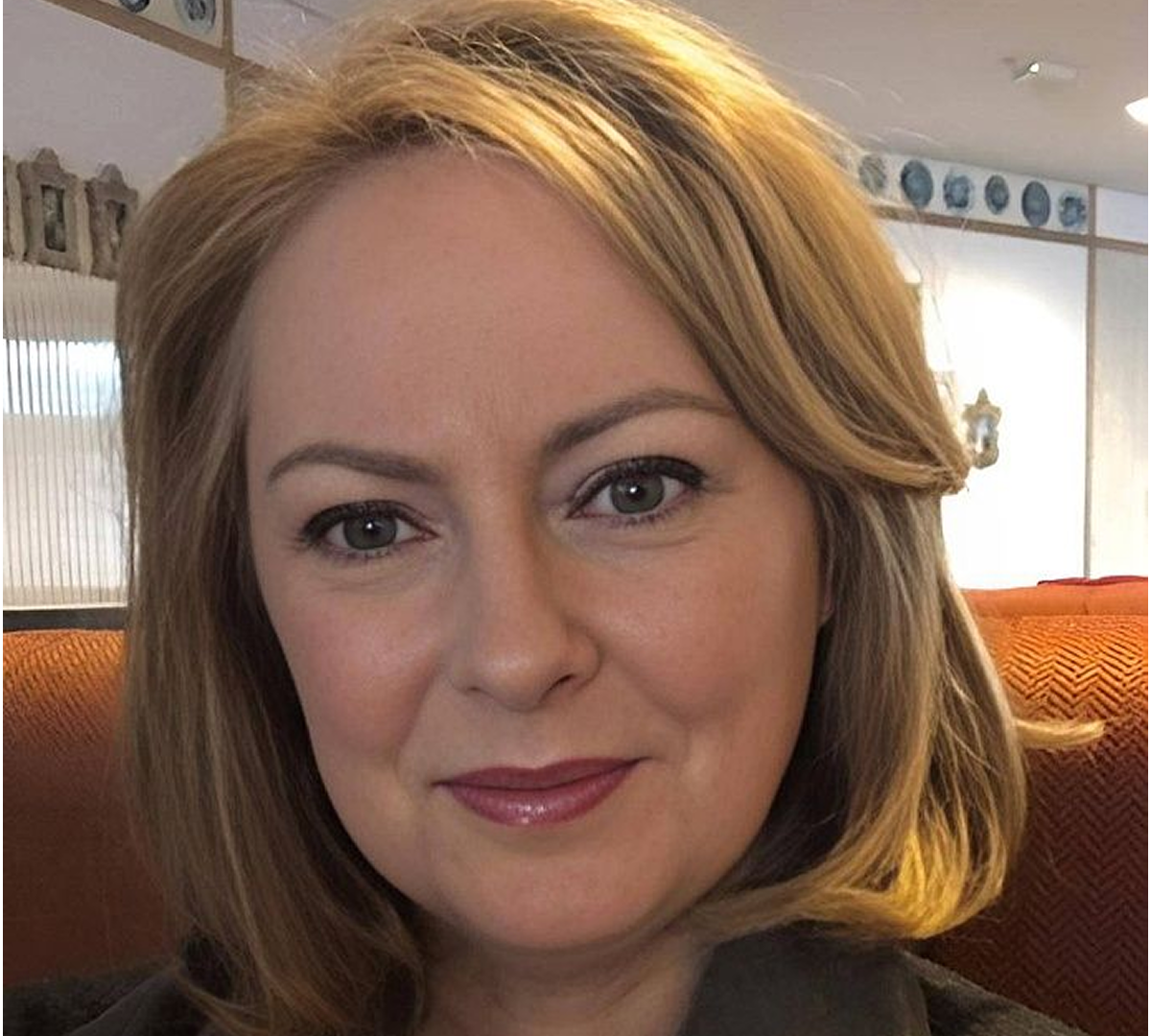 Woman with short blonde hair smiling indoors.