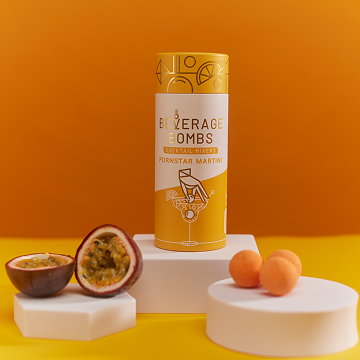 A tube of Pornstar Martini beverage bombs next to a sliced passion fruit and three small bombs.
