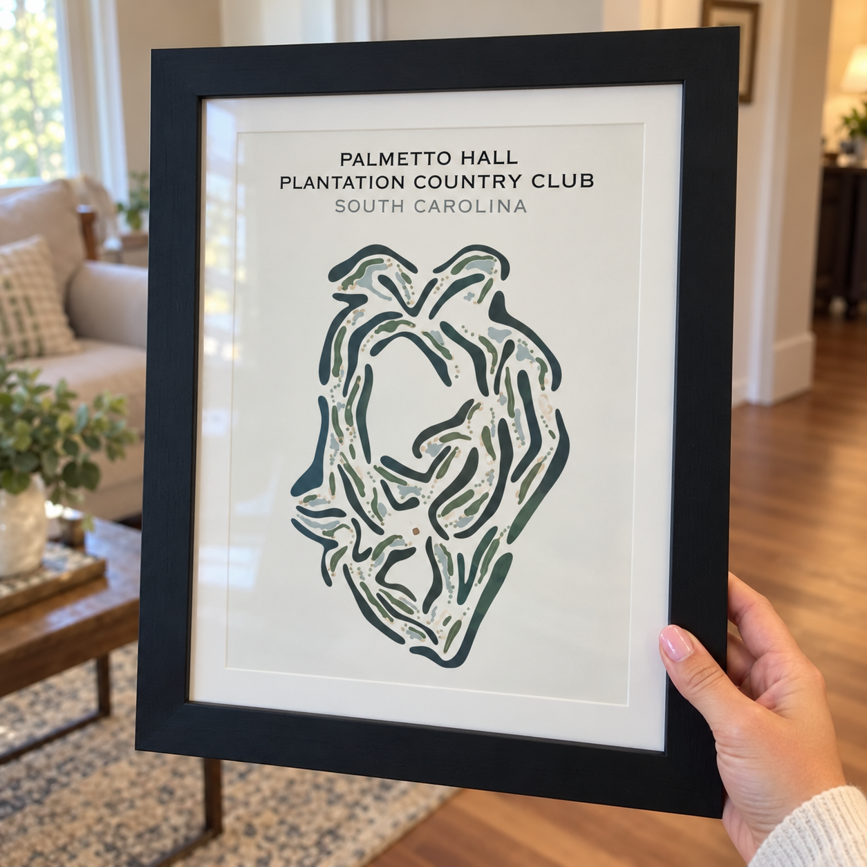 A person holding a framed art print of the Palmetto Hall Plantation Country Club golf course.