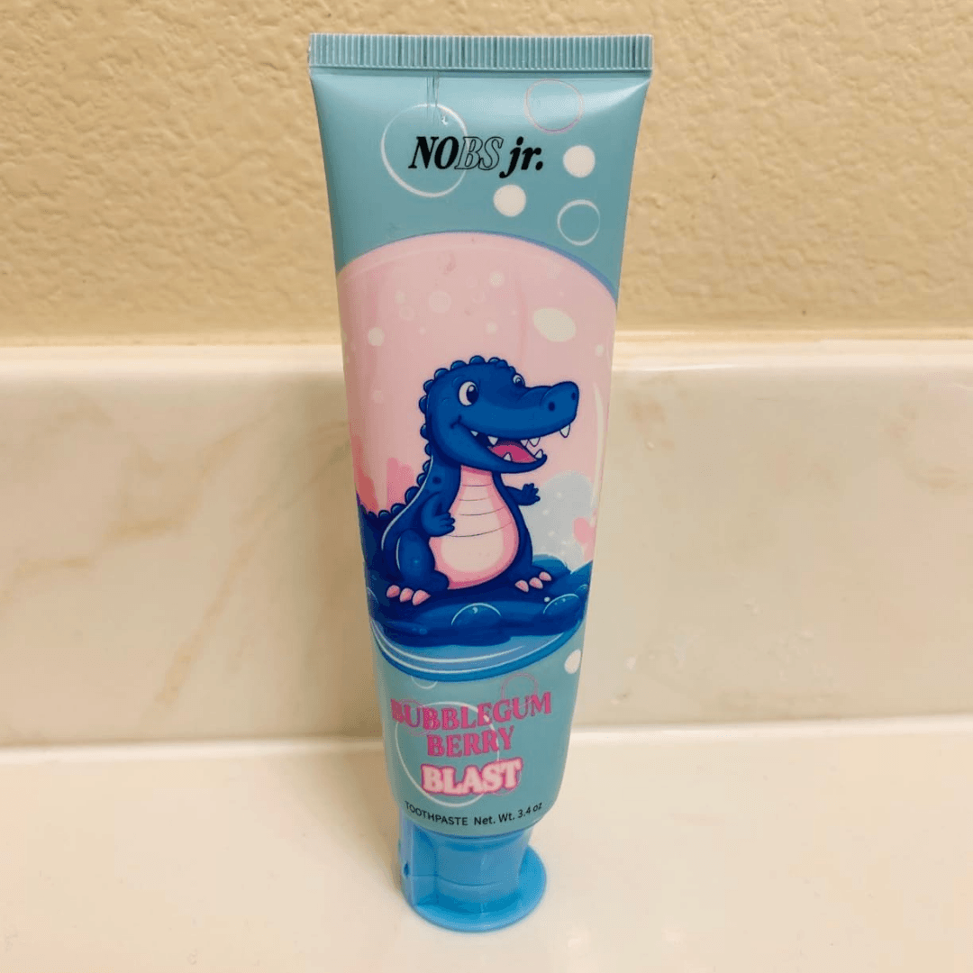 A tube of NOBS jr. Bubblegum Berry Blast toothpaste with a cartoon dinosaur on the label.