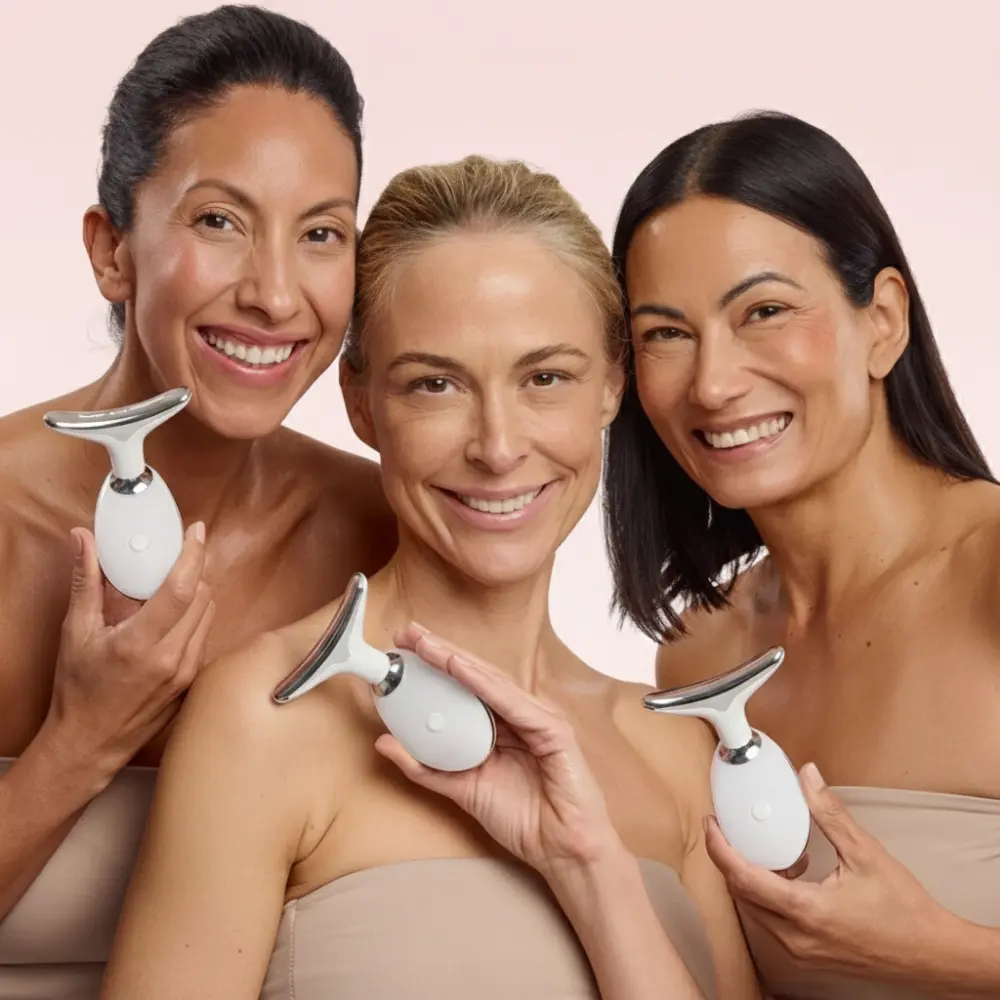 Three smiling women of diverse ethnicities hold white and silver handheld skincare devices against a light pink background.