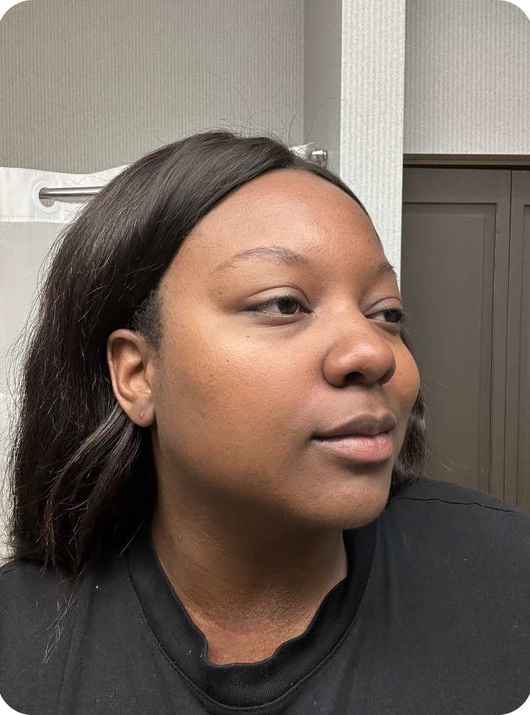 Person with dark hair looking sideways, standing indoors.