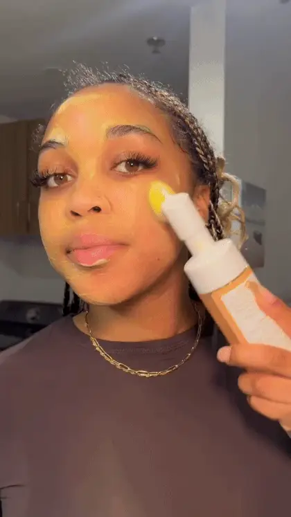 Person applying skincare product to face with a brush.