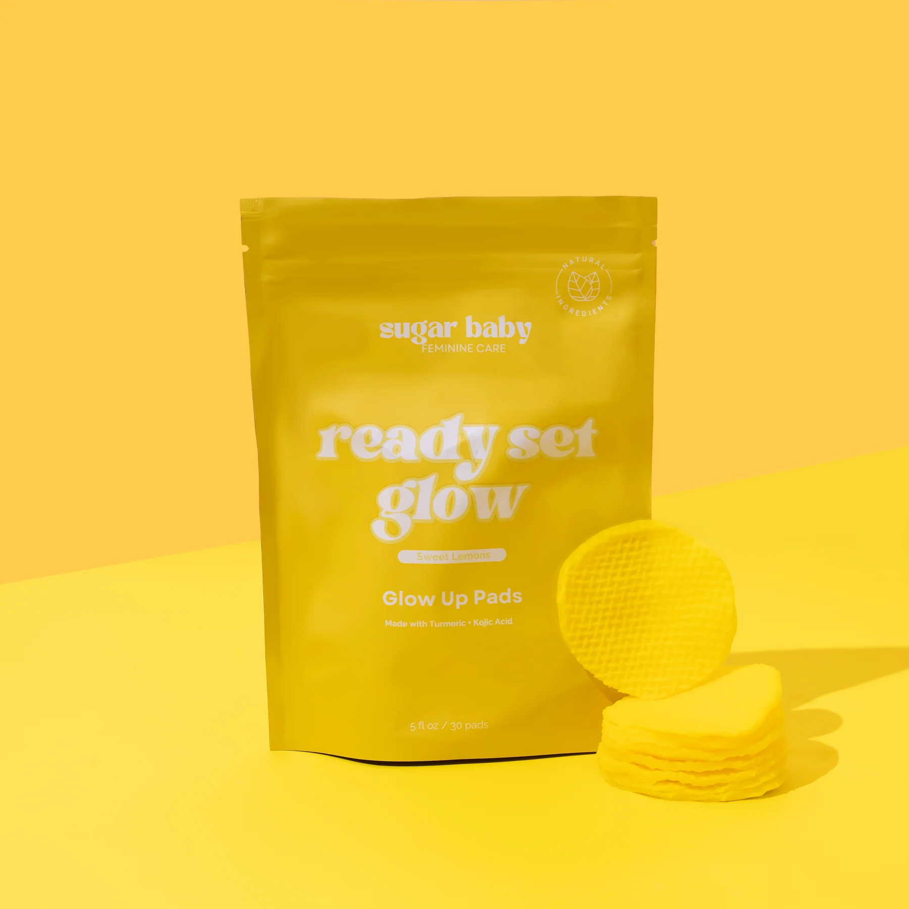 Yellow packaging of 'ready set glow' pads with stacked yellow pads.