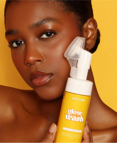 Person holding a yellow bottle labeled 'glow wash' against a yellow background.