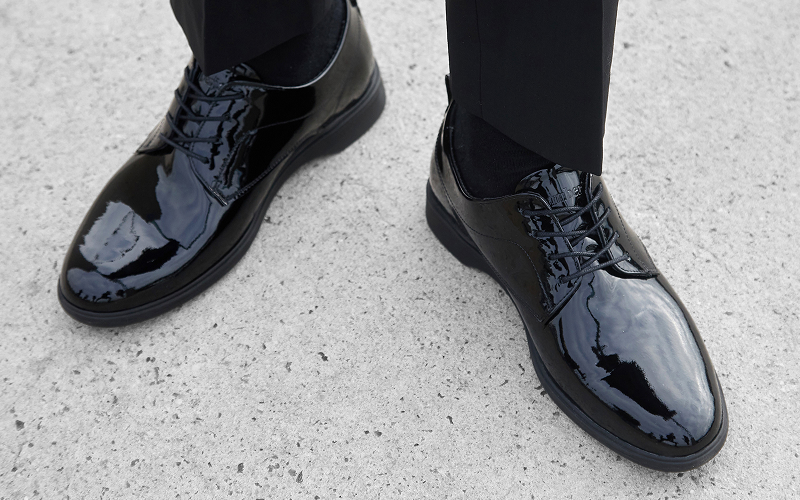 Shiny black dress shoes on a concrete surface.