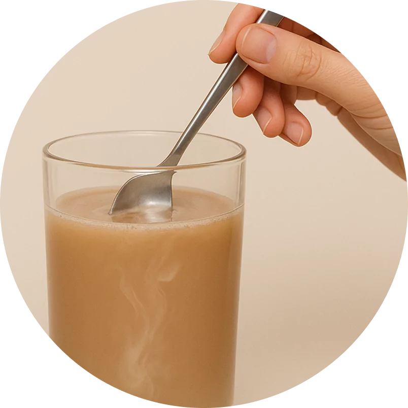 Hand stirring a steaming glass of brown liquid with a spoon.