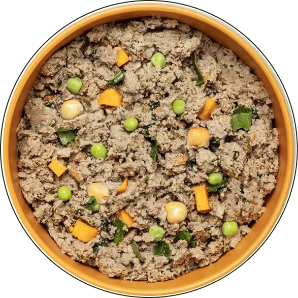 Bowl of mixed dog food with peas and cheese chunks on top.