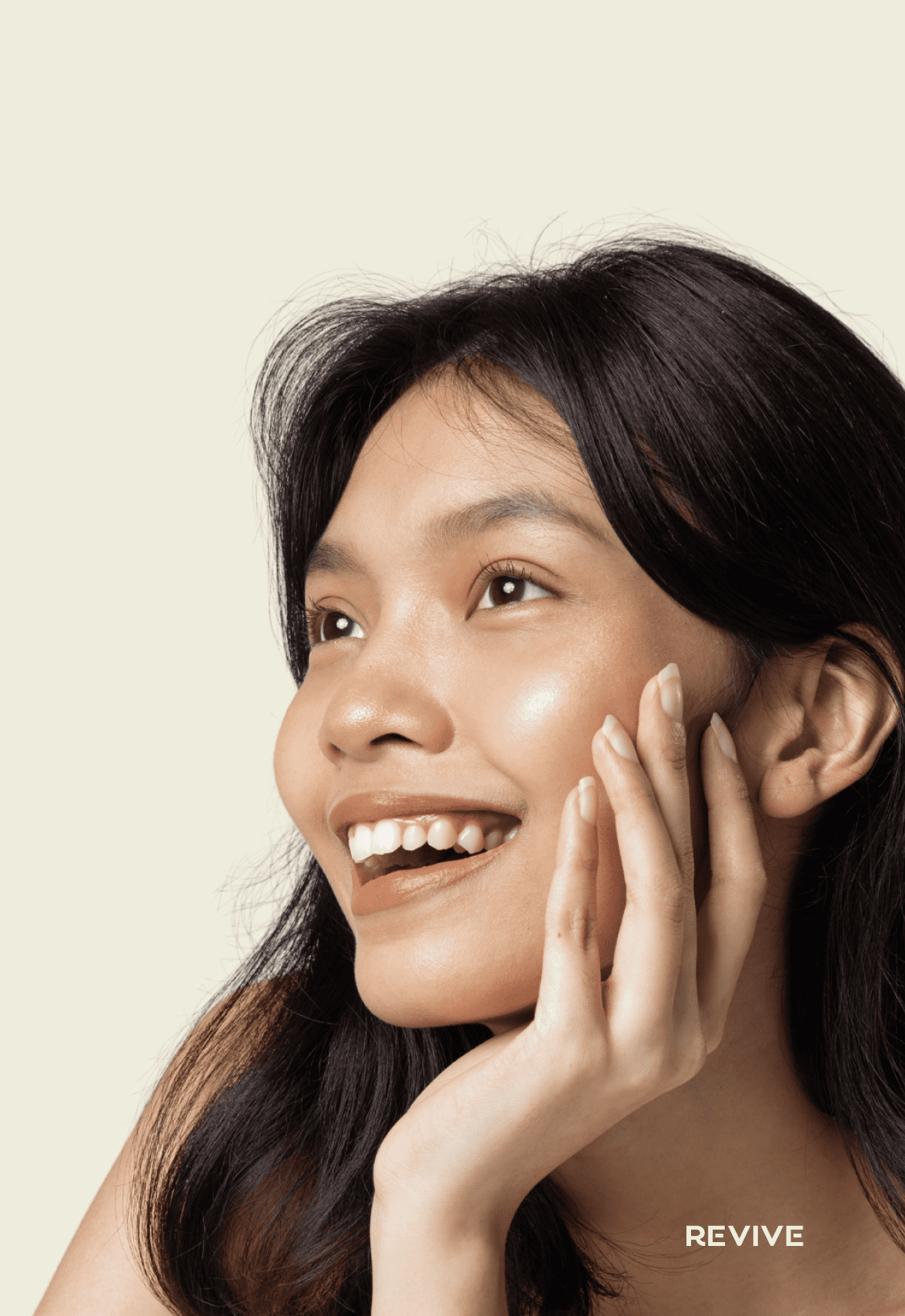Smiling person with long dark hair, hand on cheek, against a light background.
