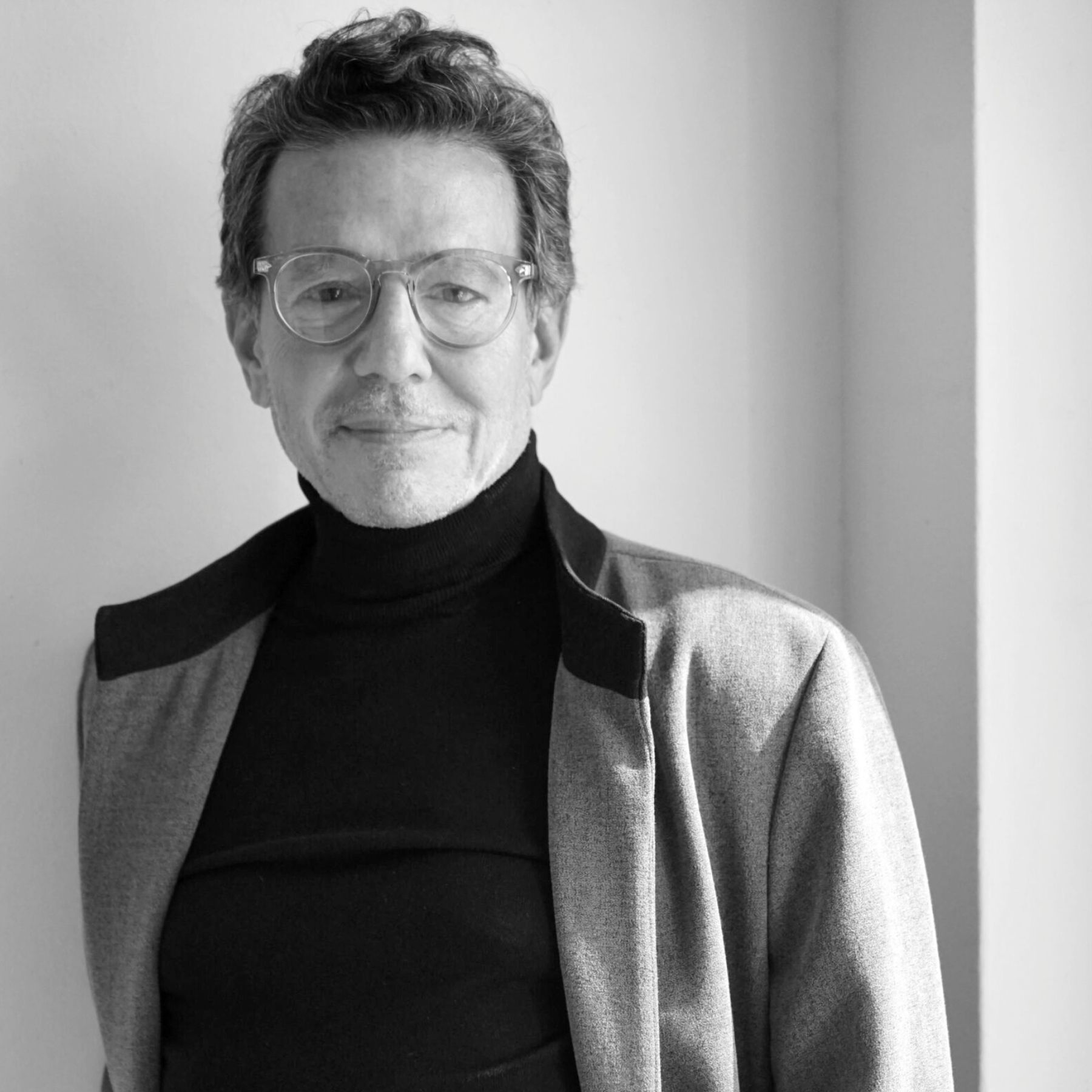 Black and white portrait of a man wearing glasses and a turtleneck.