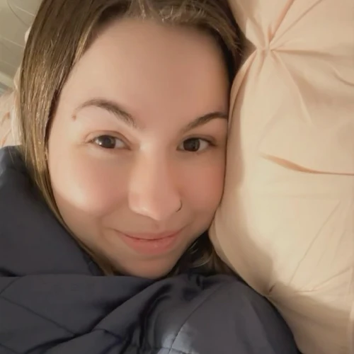 A person lying on a pillow, smiling softly at the camera.