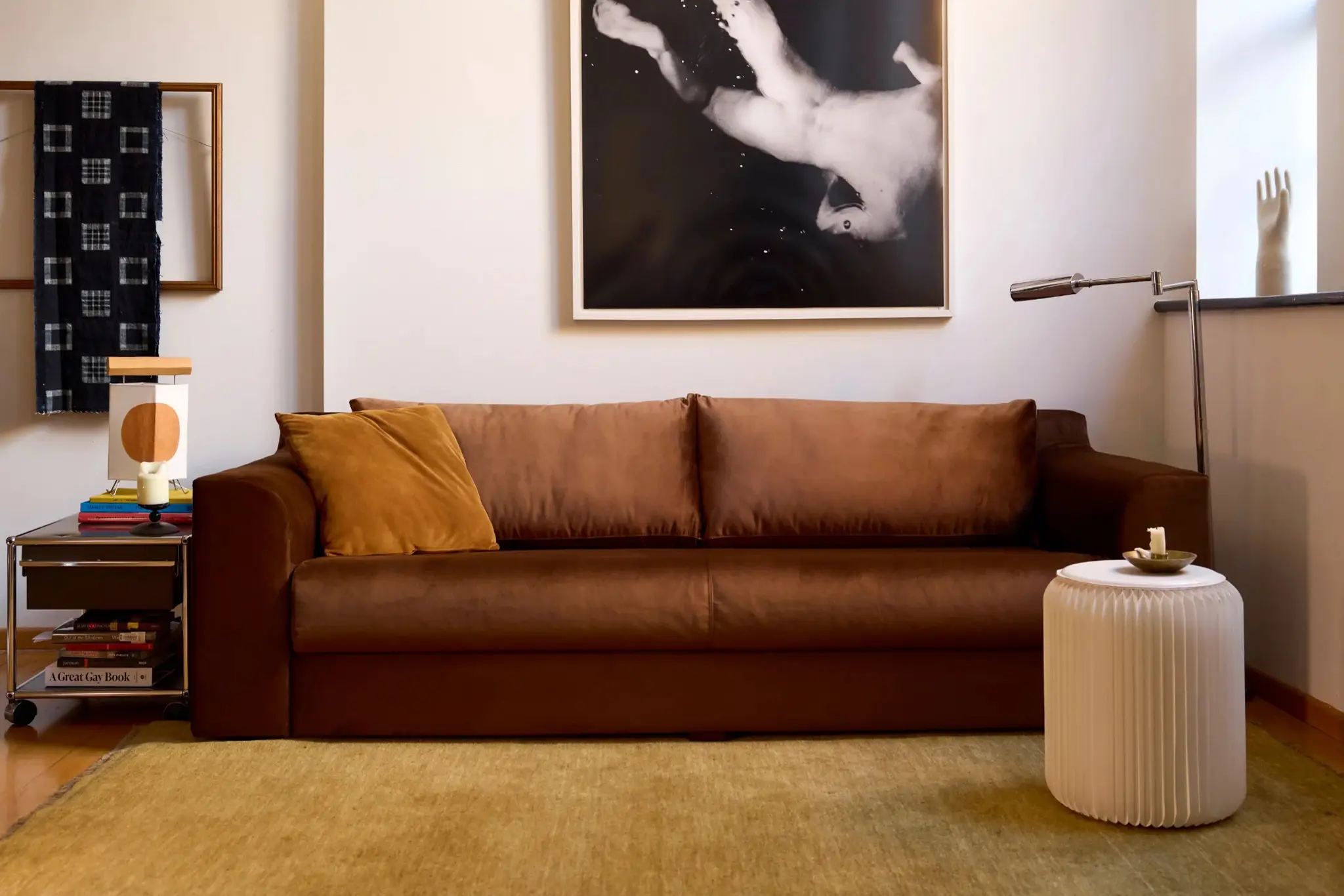 Brown sofa with yellow pillow, abstract art, side table, and lamp in a cozy living room.