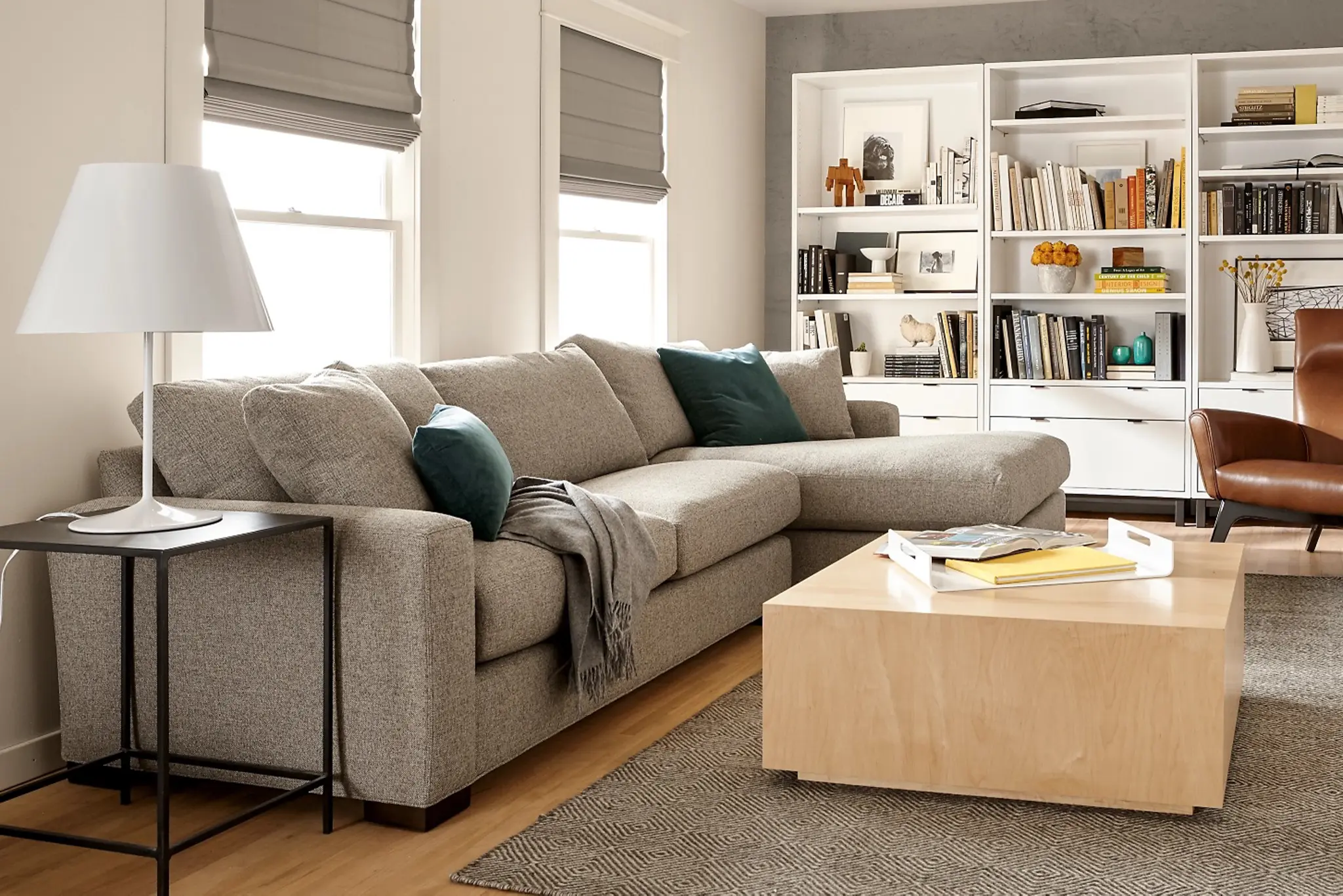 Modern living room with gray sofa, bookshelves, and wooden coffee table.