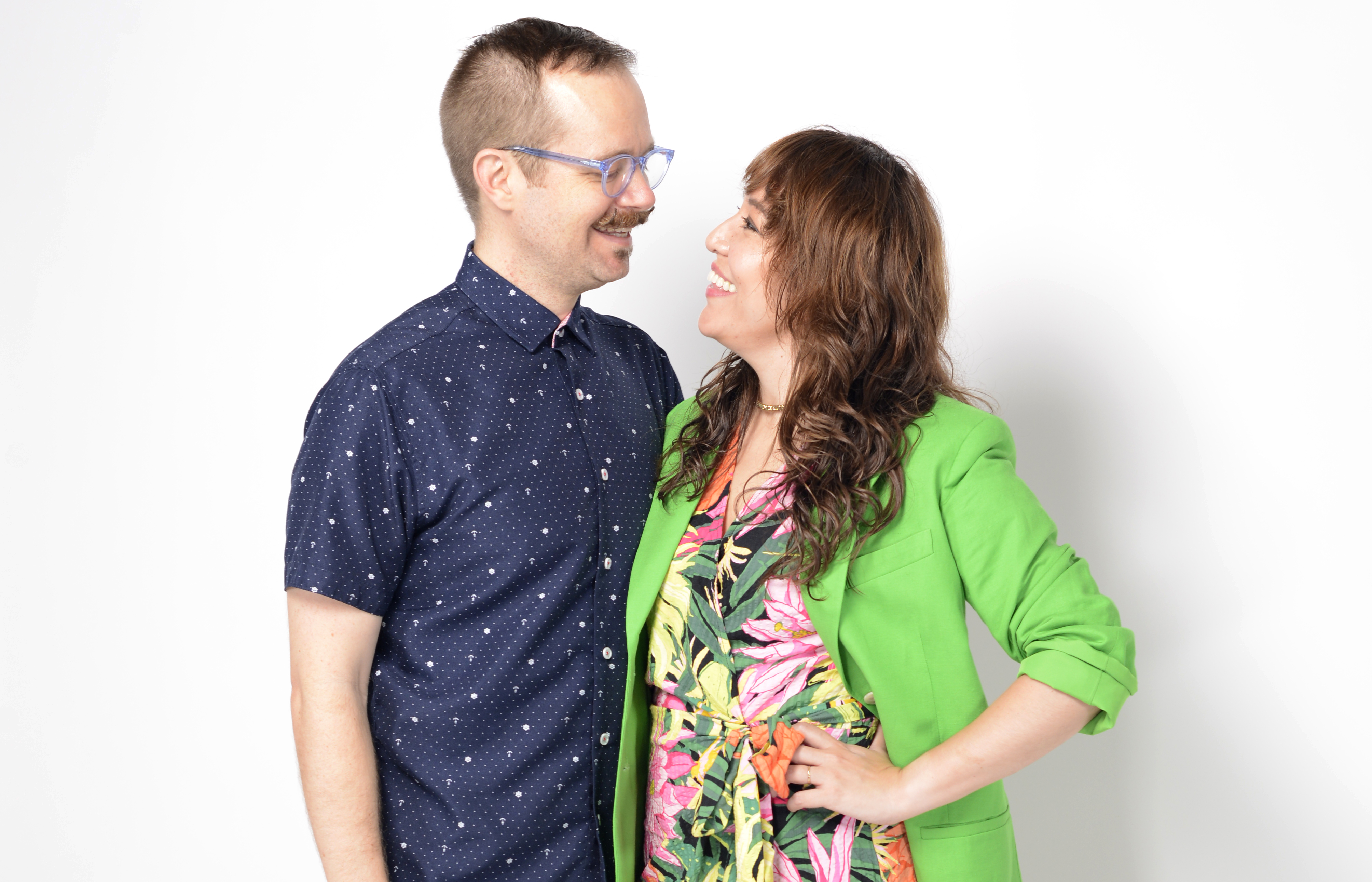 Two people smiling at each other against a white background.