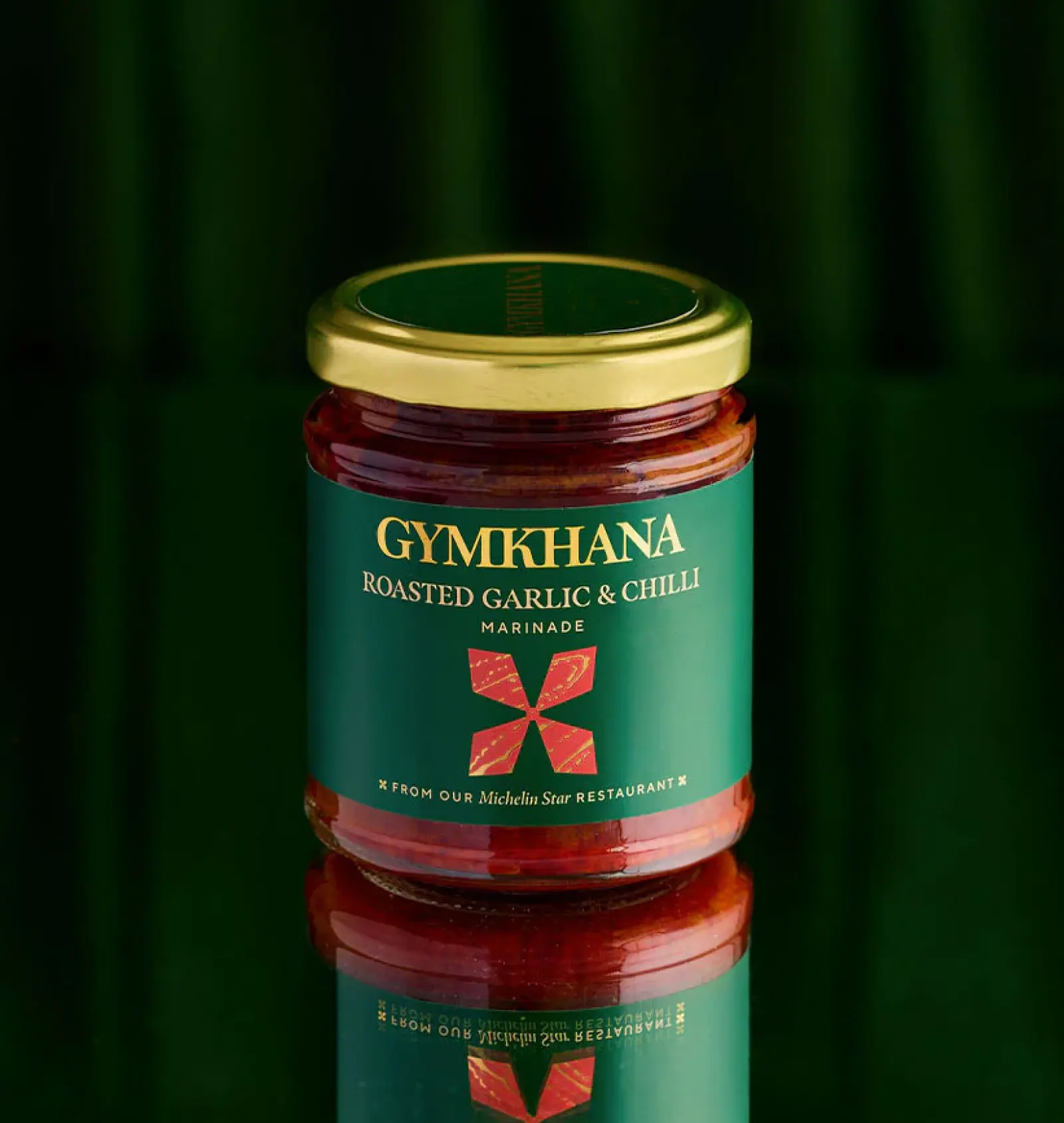 Jar of Gymkhana roasted garlic and chilli marinade on reflective surface.