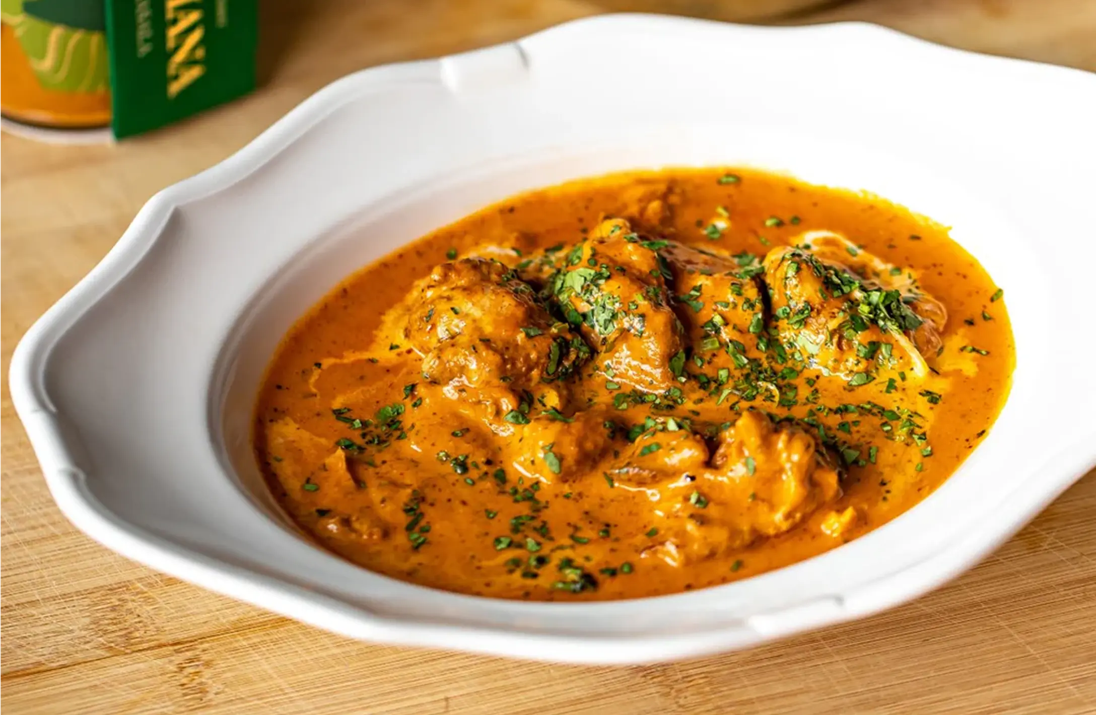 A package of Gymkhana Chicken Tikka Thighs showing the cooked product on a silver platter with chutney.