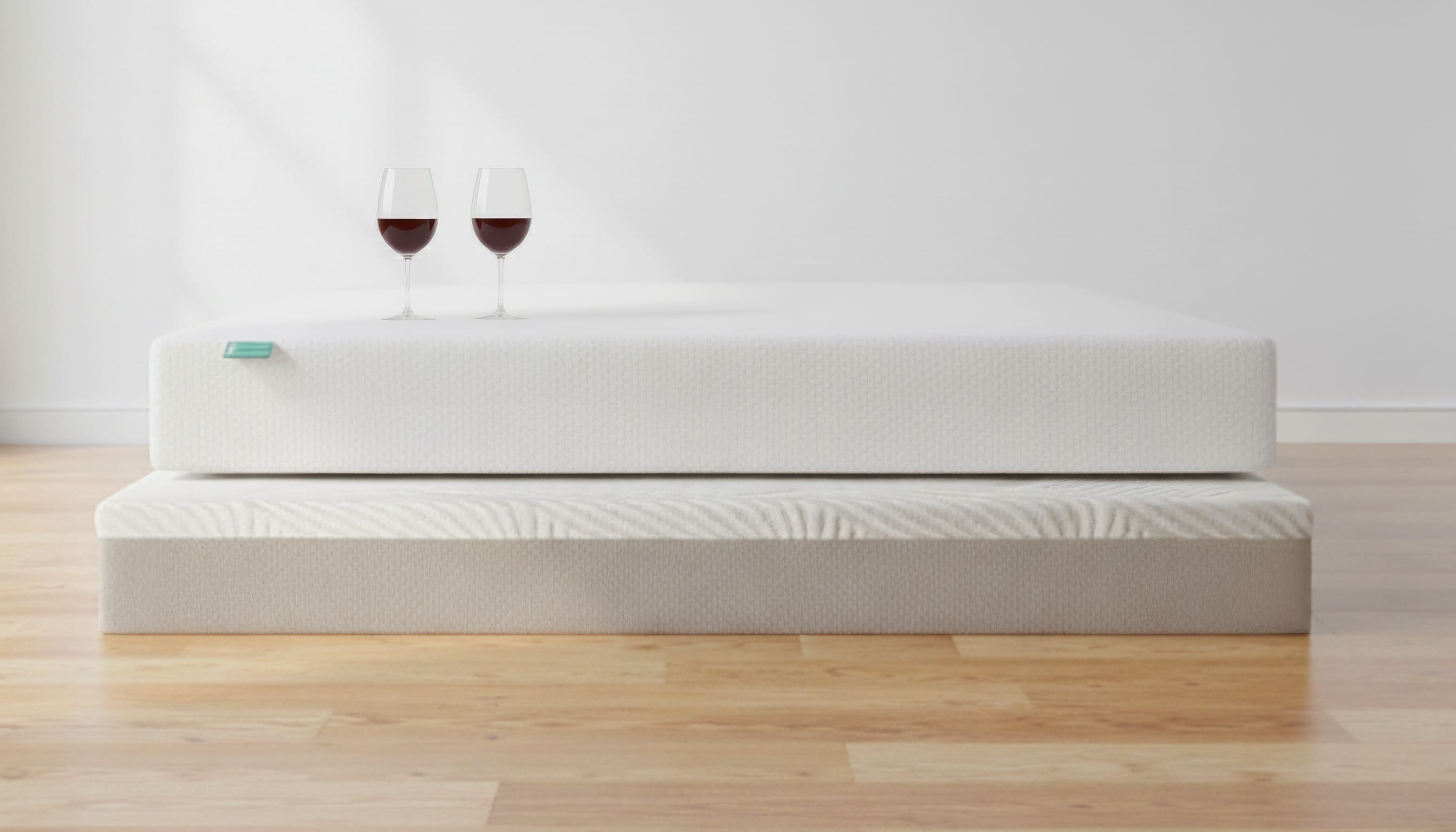 Clean, white mattress with 2 glasses of wine sitting on top.