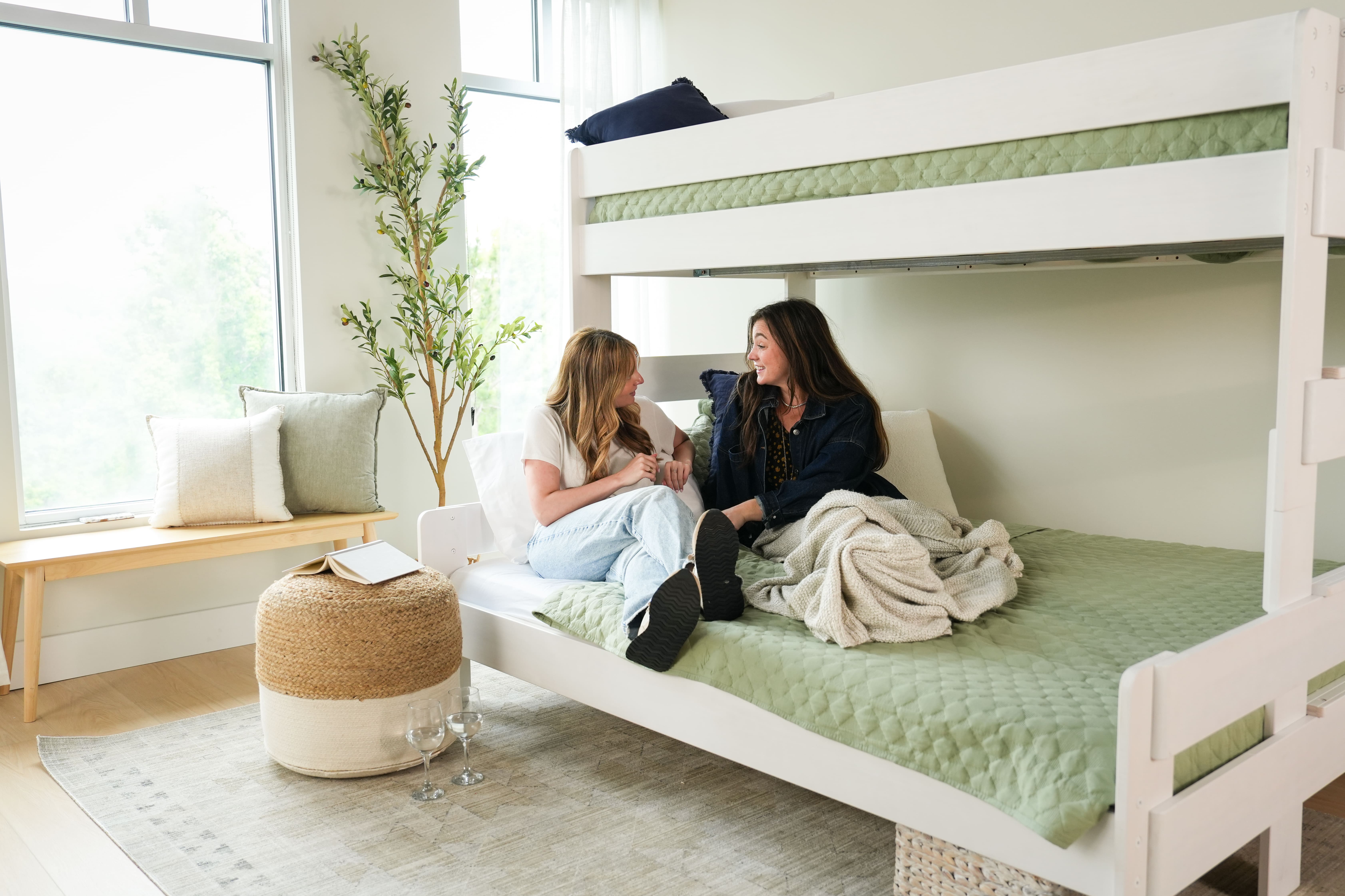 Two people sitting on the bottom bunk of a bunk bed talking.
