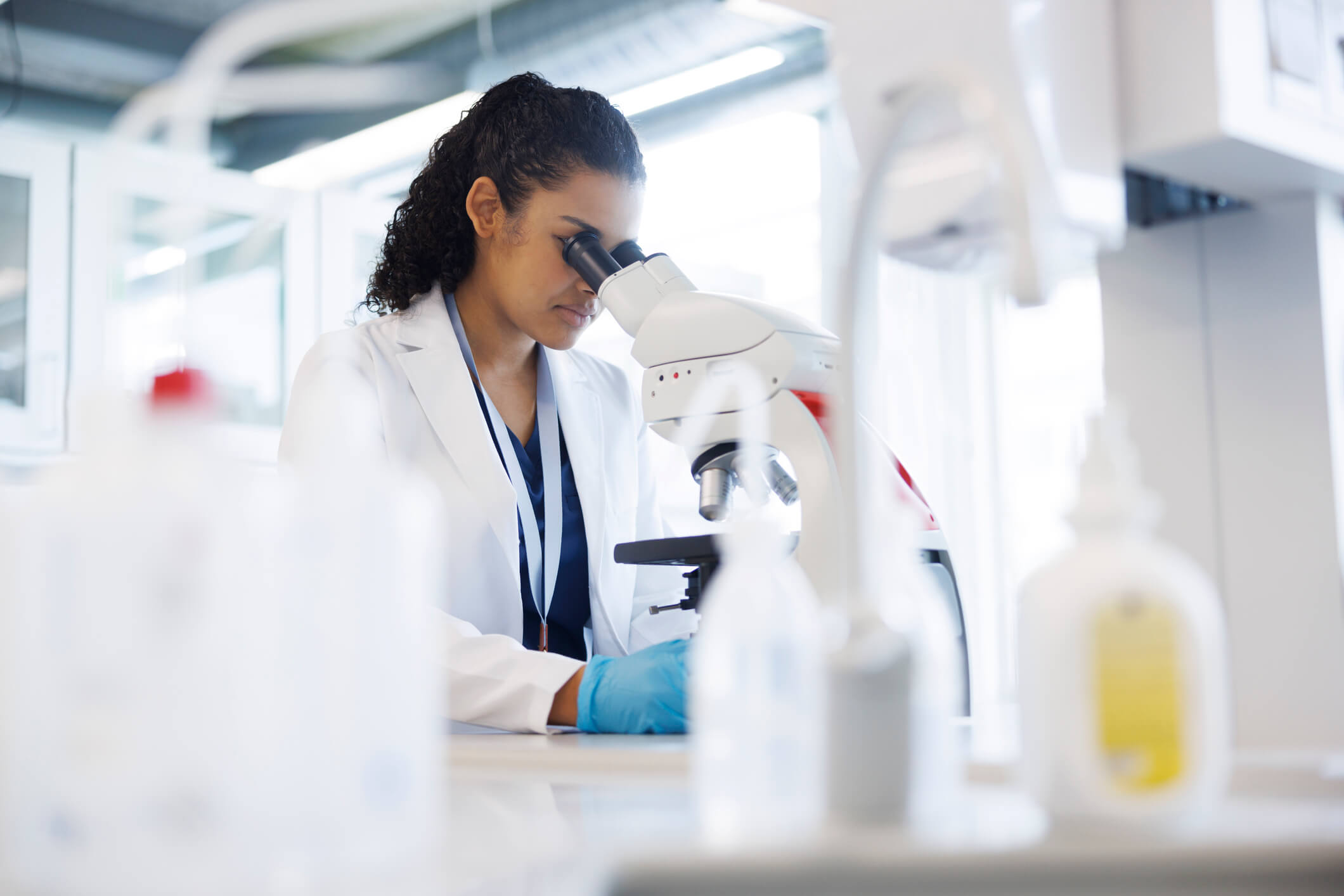 Scientist examining samples under a microscope in a laboratory.