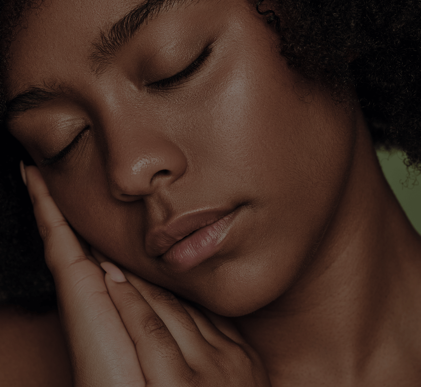 A person peacefully resting with eyes closed and hand touching face.