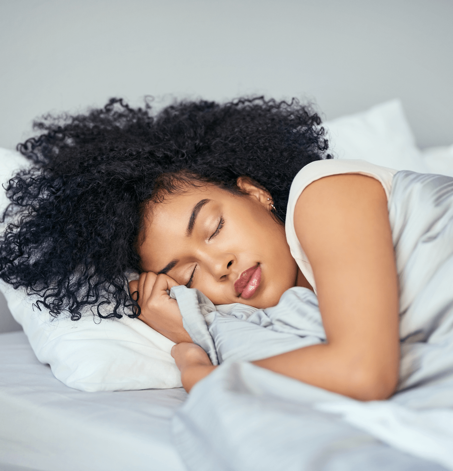 Person sleeping peacefully on a bed with white bedding.