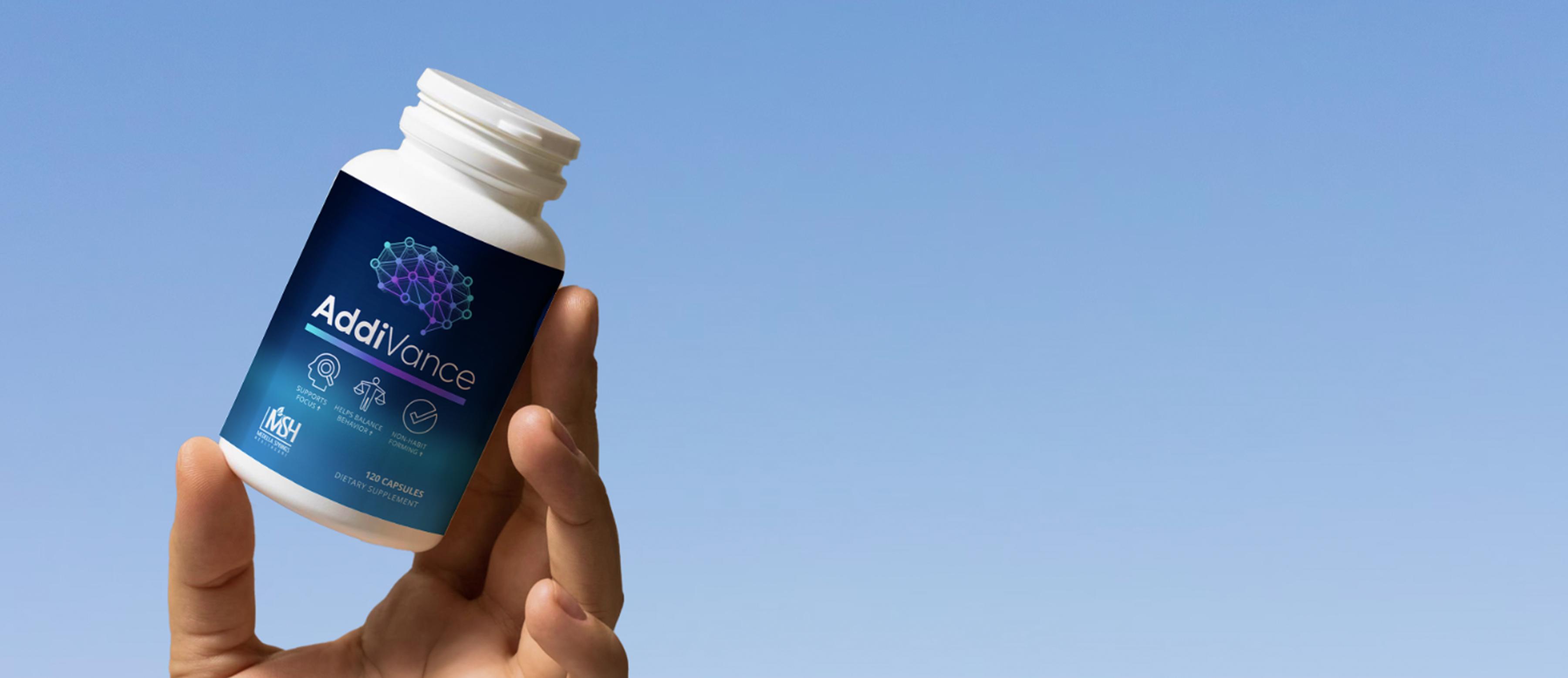 Hand holding a supplement bottle labeled 'AddiVance' against a clear blue sky.